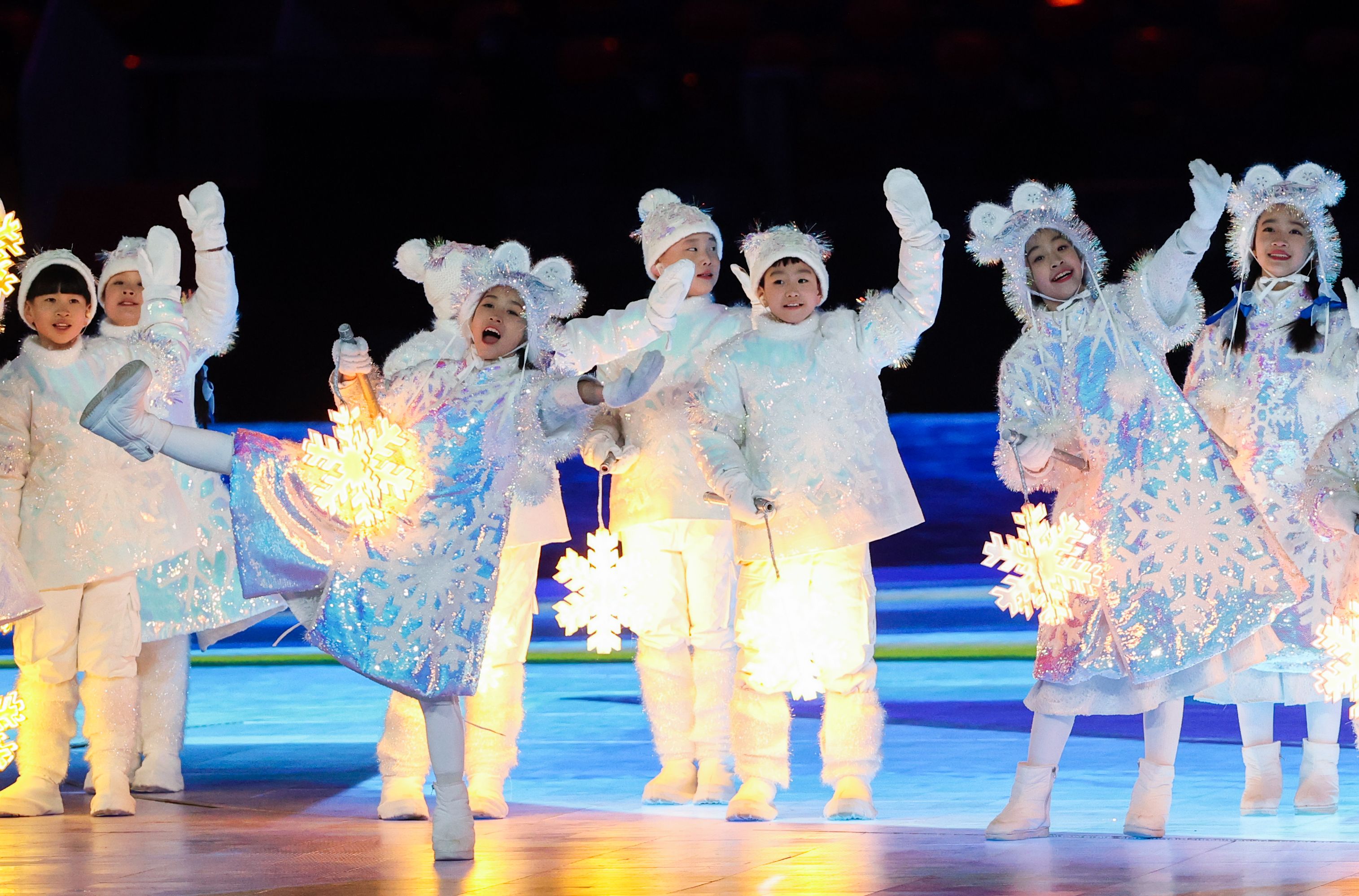 Children holding lit snowflake figures perform at the closing ceremony of the beijing games