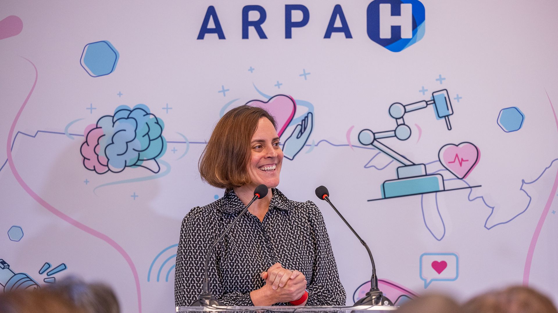 A woman with her hands clasped at a podium