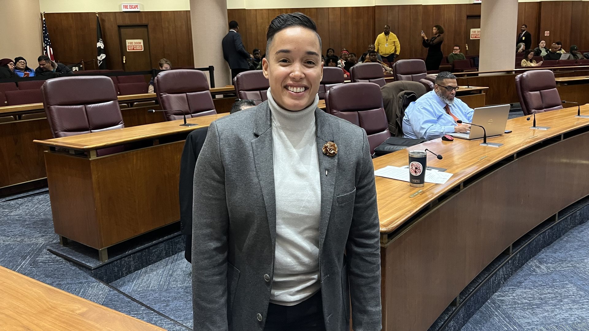 Jessie Fuentes in front of empty chairs at City Council chambers.