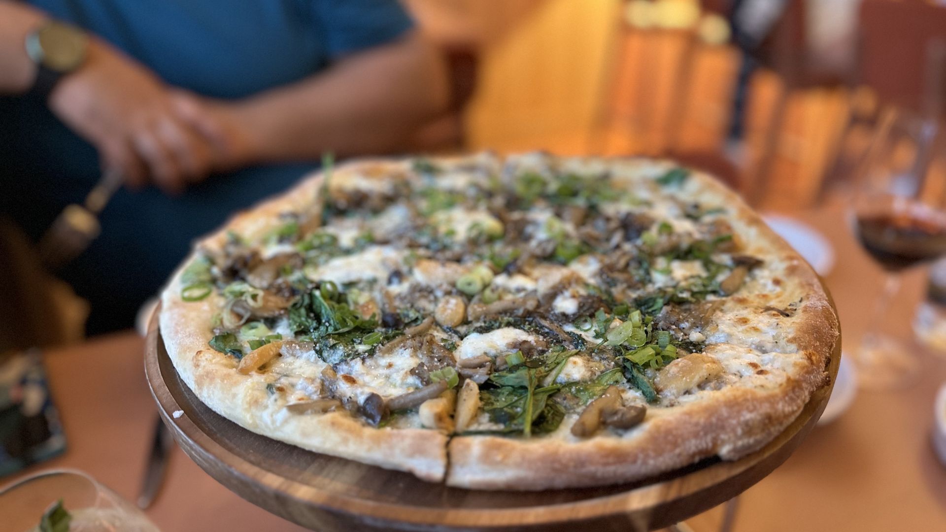 Gufo's roasted mushroom pizza with fontina and roasted garlic is served on a platter at a table.