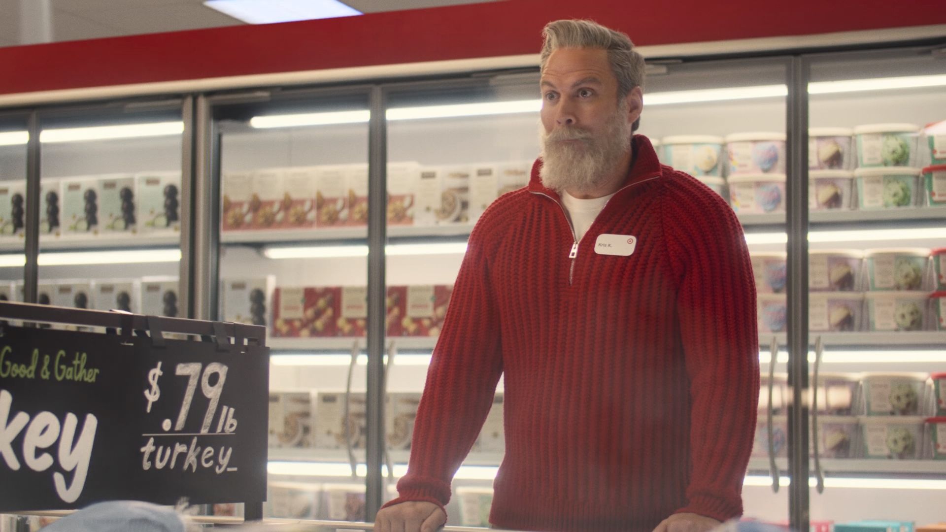 A photo of a man with white hear and beard wearing a red sweater in a target store 