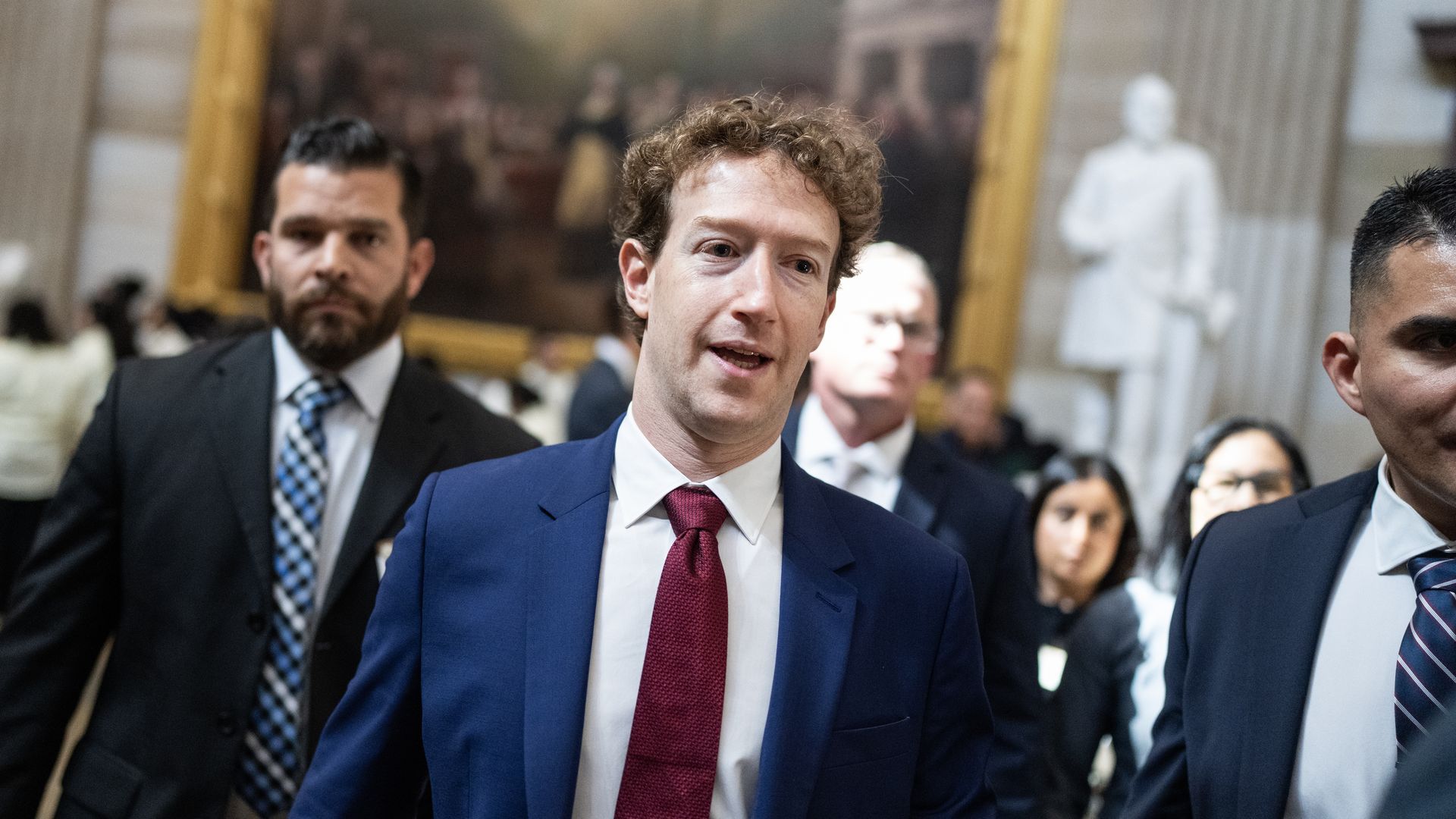 A person walking in a red tie and blue suit