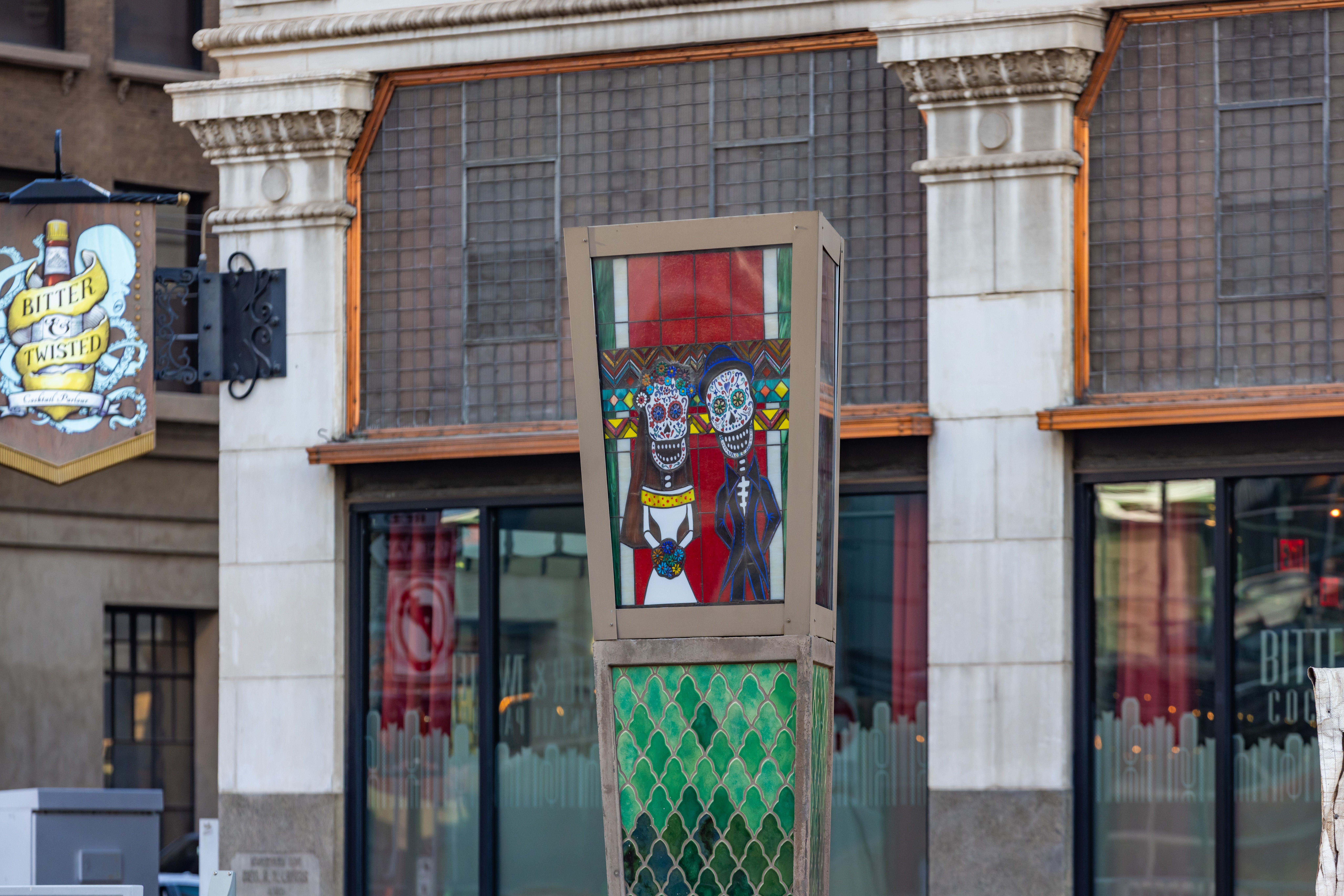 A four-sided pillar with a colorful image of a skeletal bride and groom on one side. 