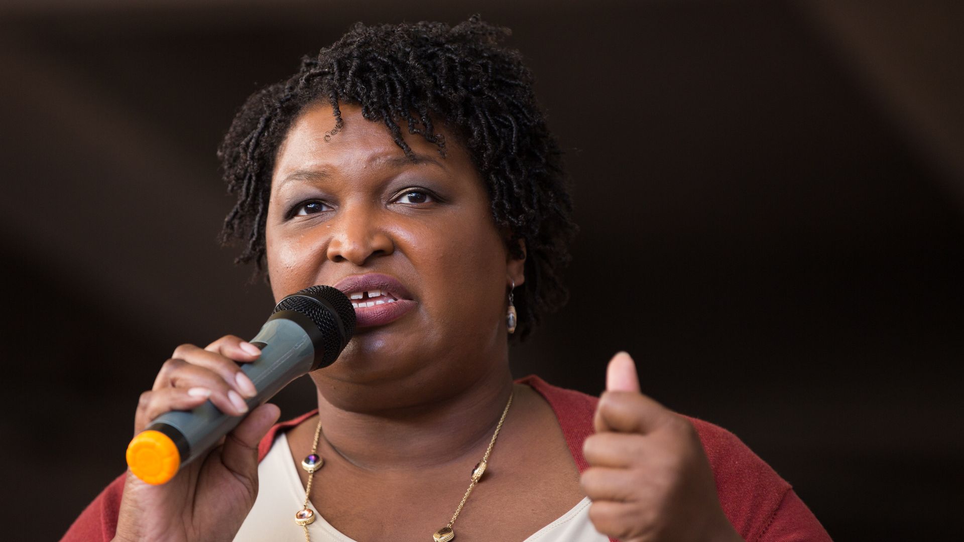 In this image, Abrams speaks to a crowd while holding a microphone.