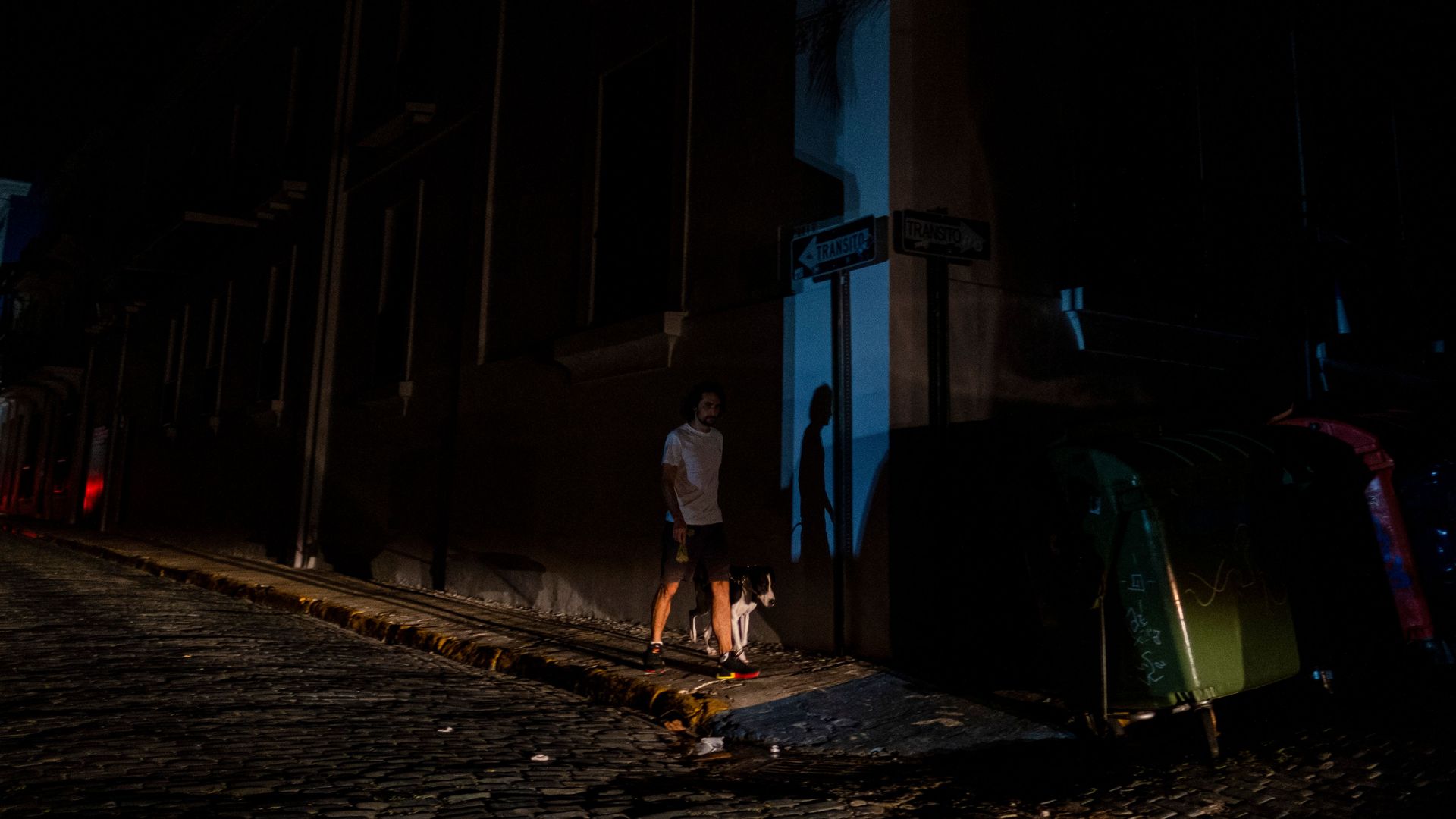 A man walks his dog in a street left in darkness by a power outage due to a cyberattack in Old San Juan, Puerto Rico, June 10, 2021.
