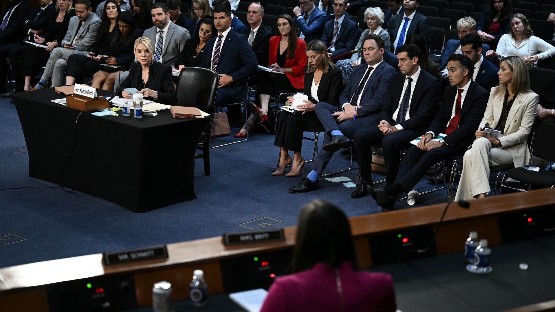 US Attorney General Pam Bondi sits at a desk while testifying on DOJ oversight. 