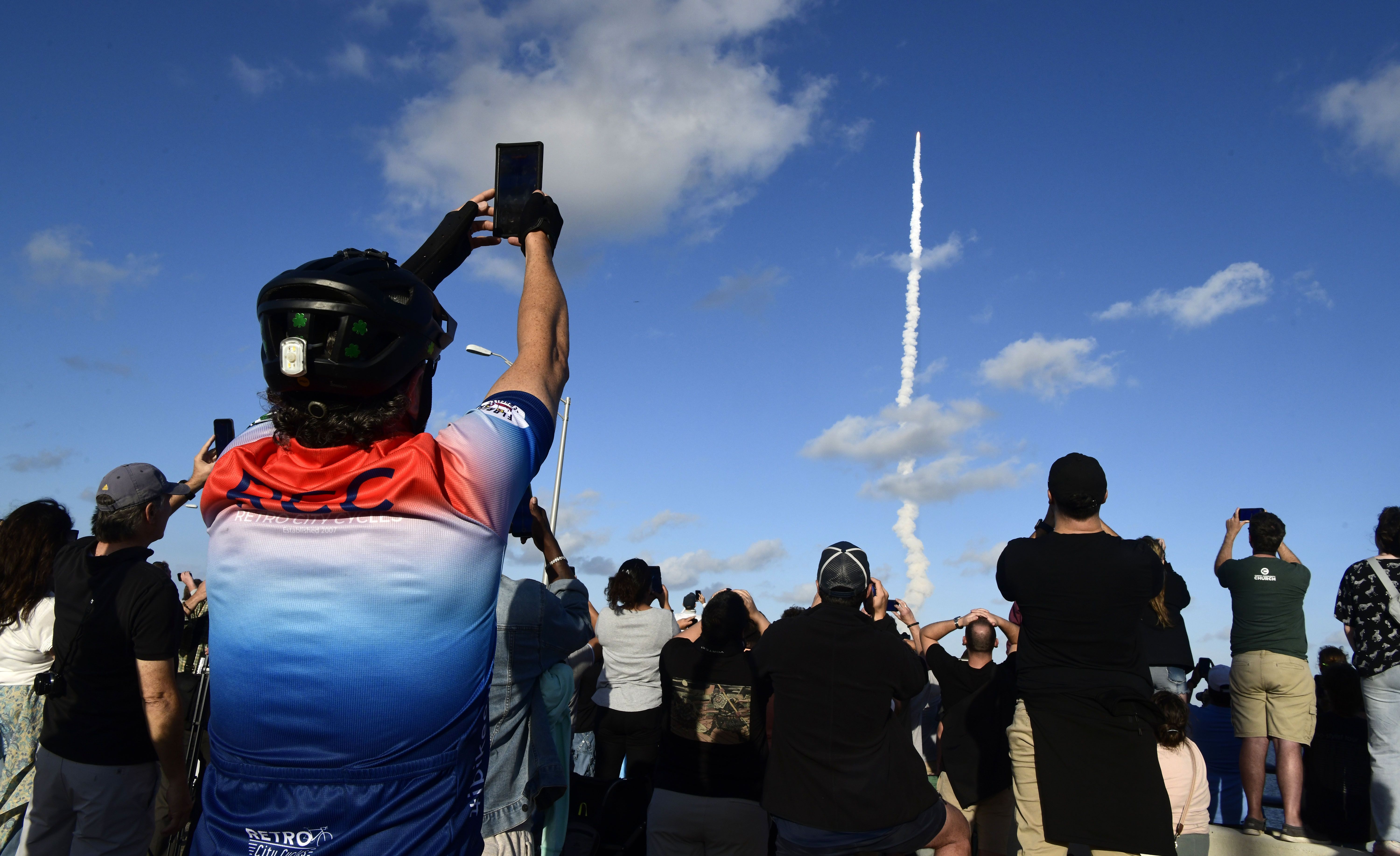 Spectators gathered on a bridge in Titusville, Florida, watch a rocket launch into the sky from Cape Canaveral.