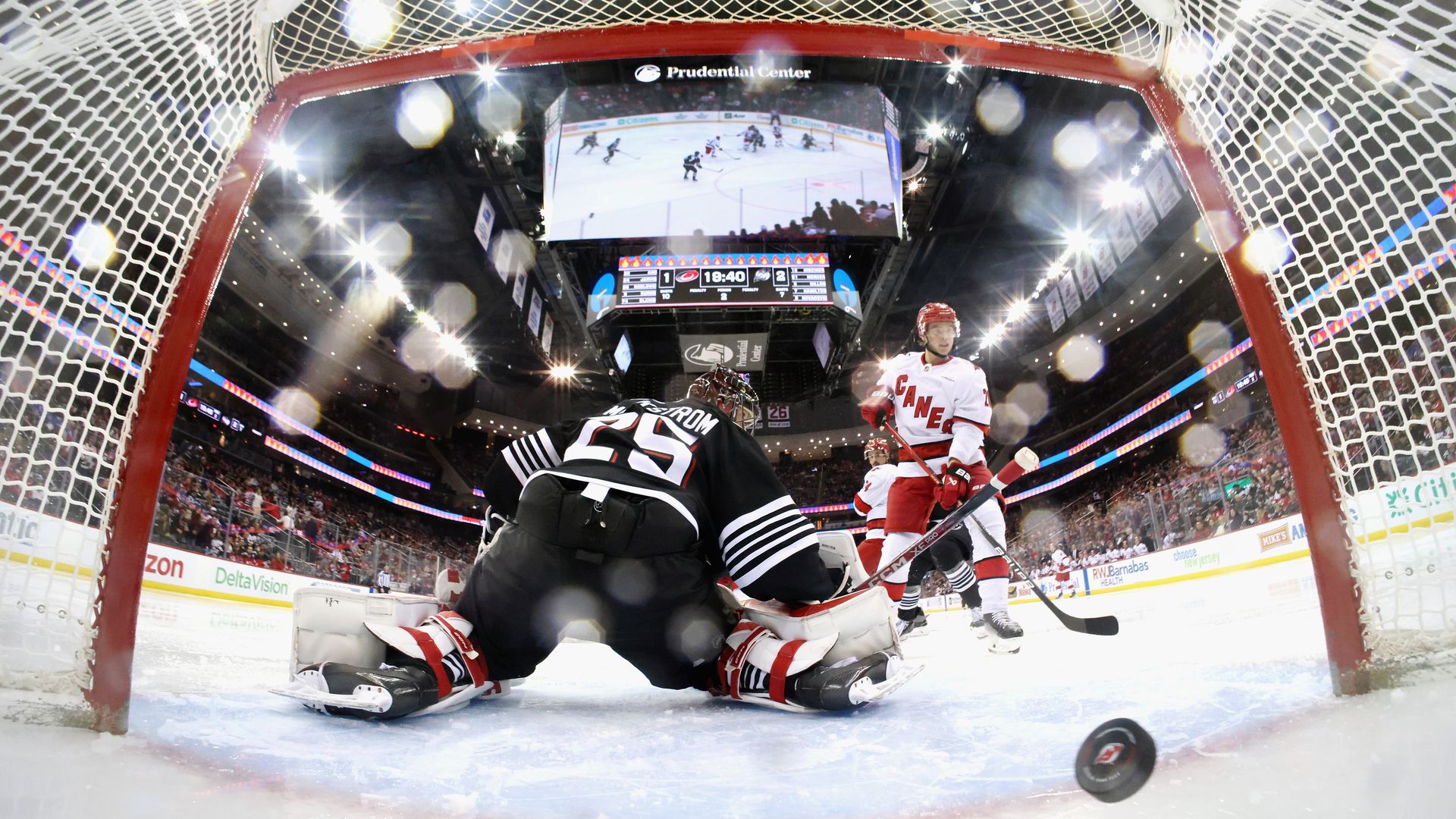 NEWARK, NEW JERSEY - DECEMBER 27: Sebastian Aho #20 of the Carolina Hurricanes watches a second period shot by Brent Burns #8 get past Jacob Markstrom #25 of the New Jersey Devils at Prudential Center on December 27, 2024 in Newark, New Jersey. The Devils defeated the Hurricanes 4-2. (Photo by Bruce