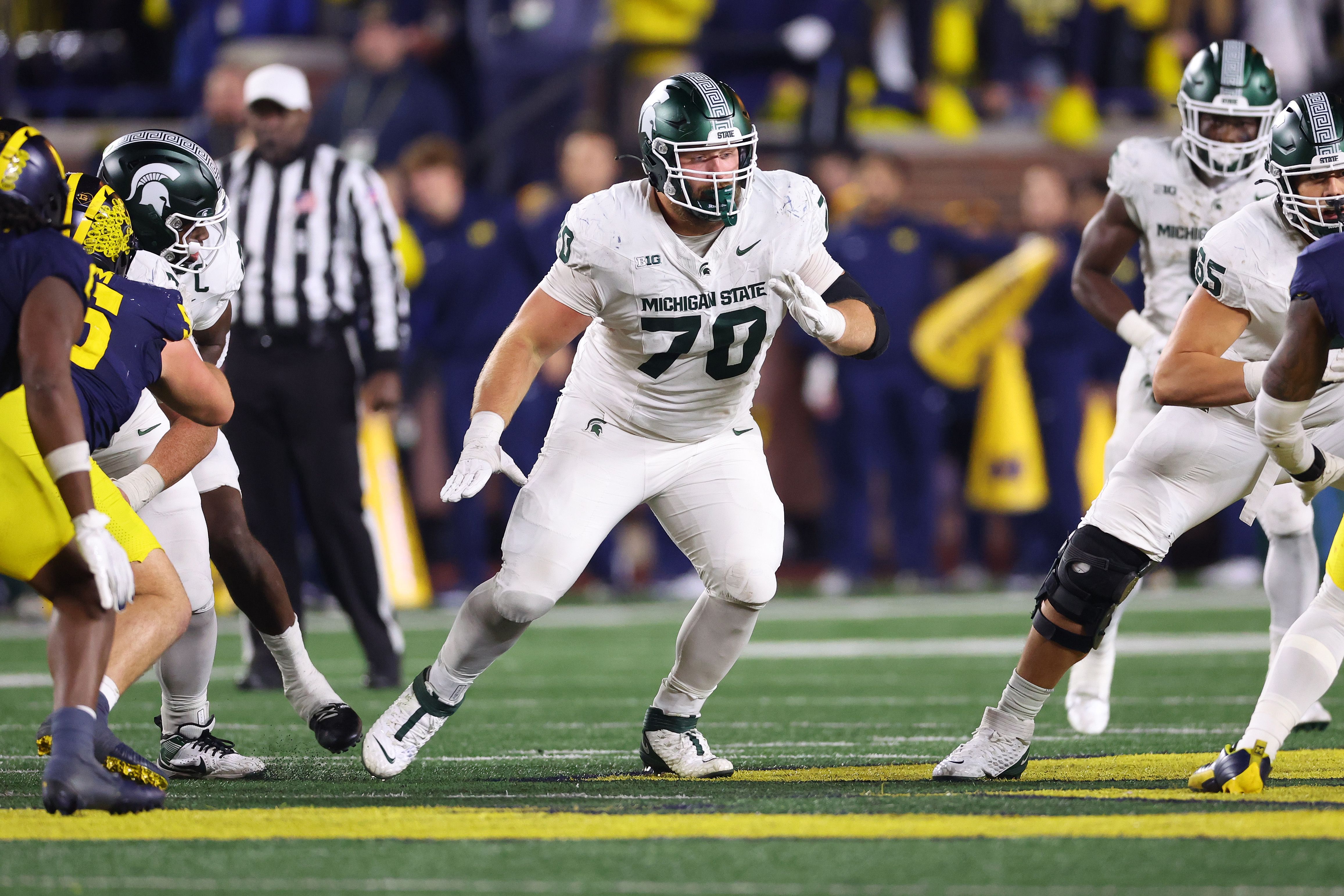 Photo of a football player blocking other football players in a game. 