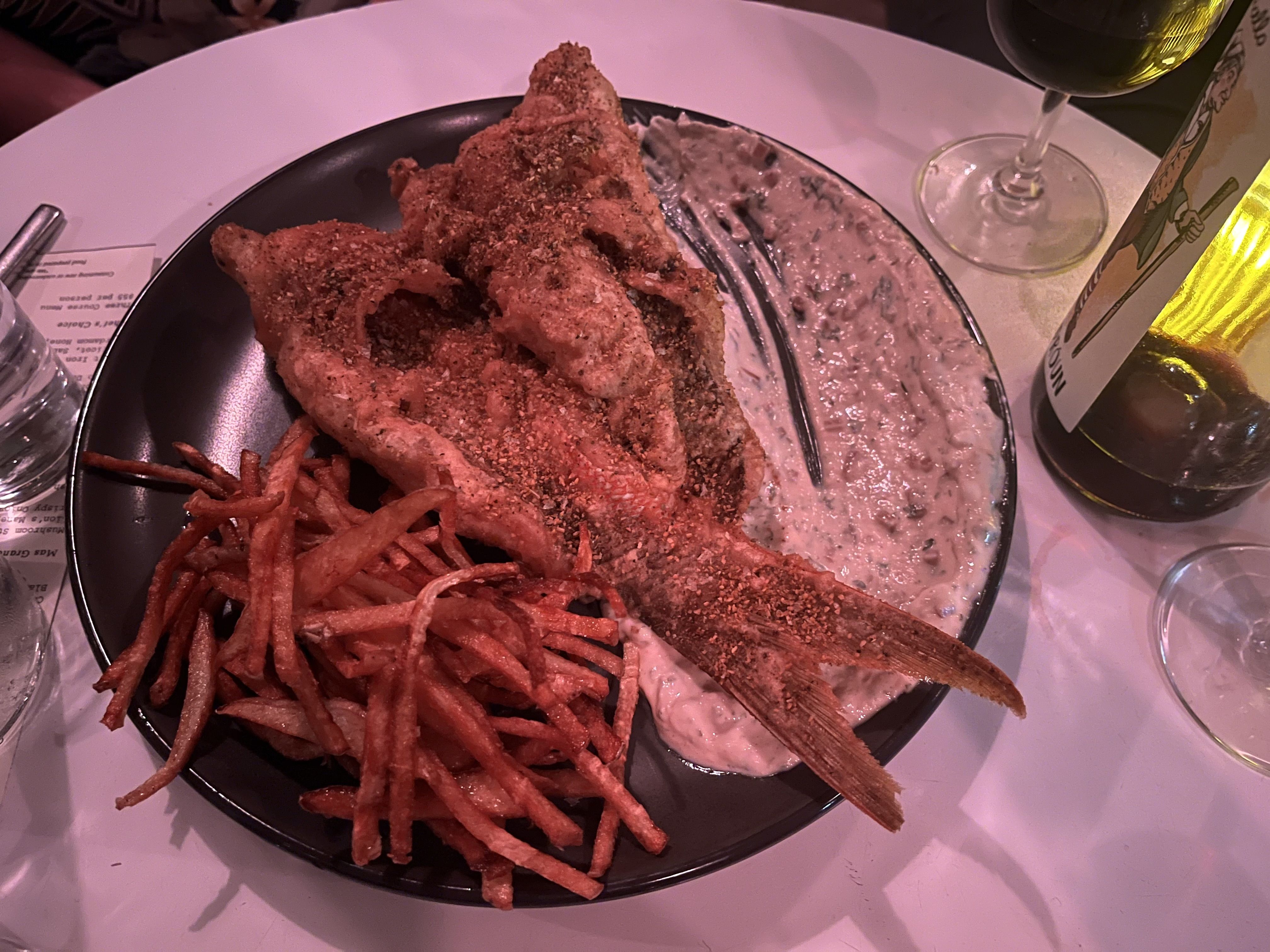 A plate with a whole fried fish and french fries.