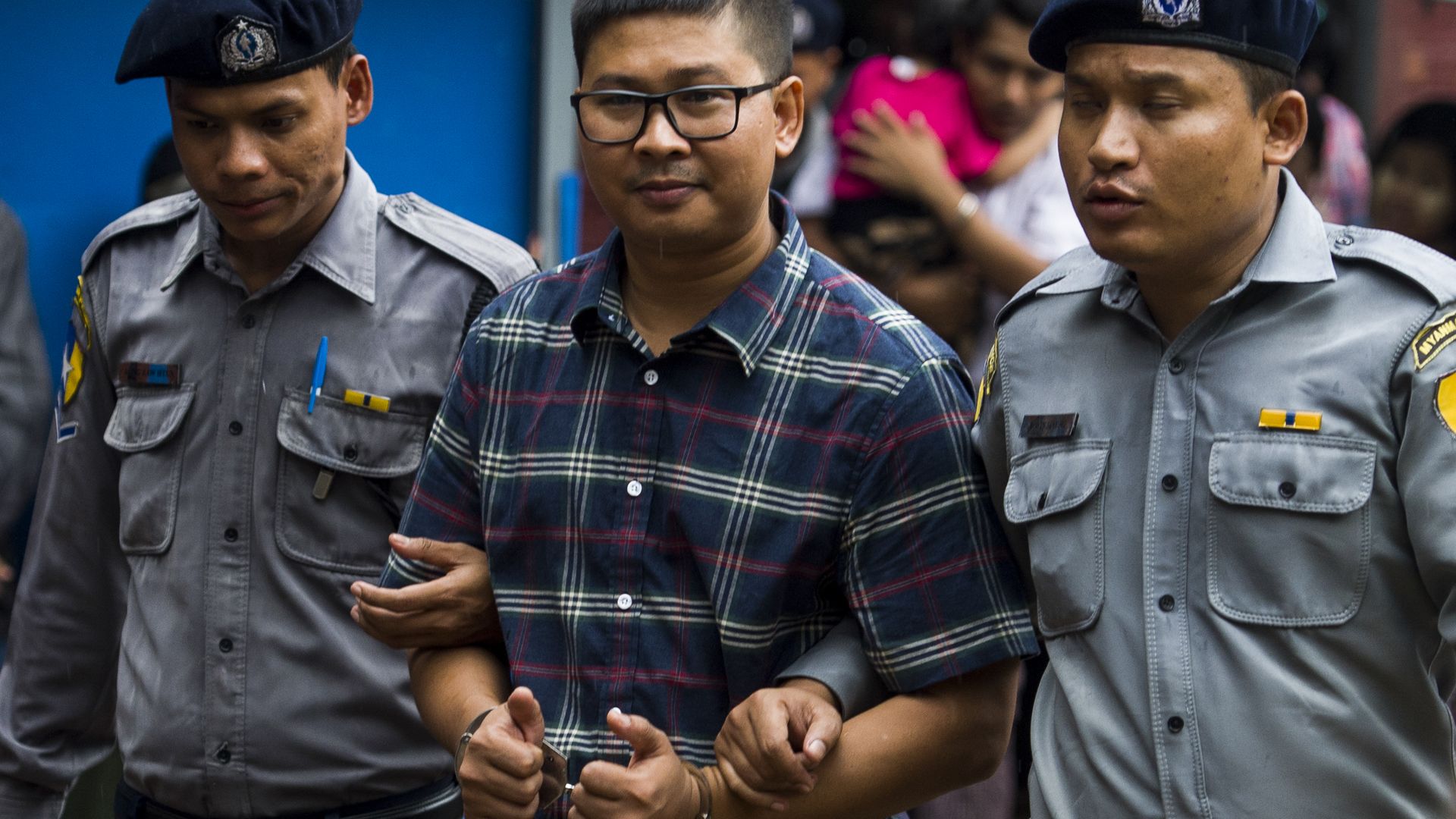 Journalst Wa Lone gives a thumbs-up as he's led by police.