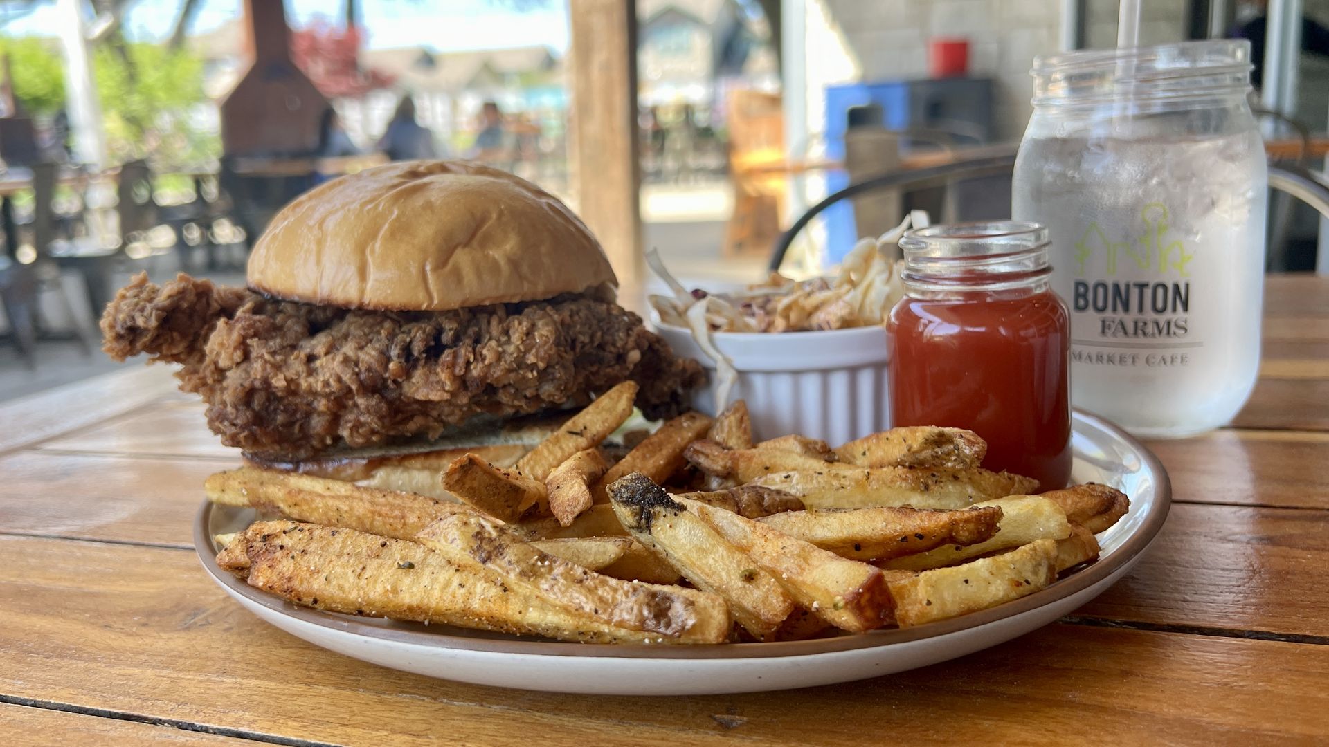 A plate of fried chicken sandwich, fries and ketchup in an outdoor setting