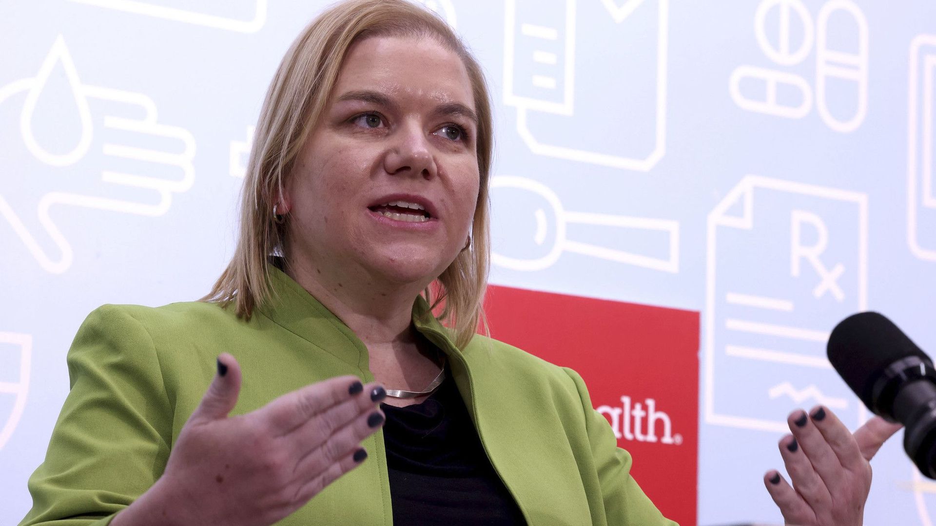 Woman with green jacket at a podium