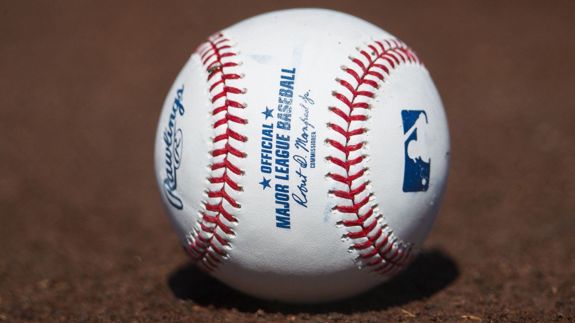 Photo of a white baseball sitting on a dirt field