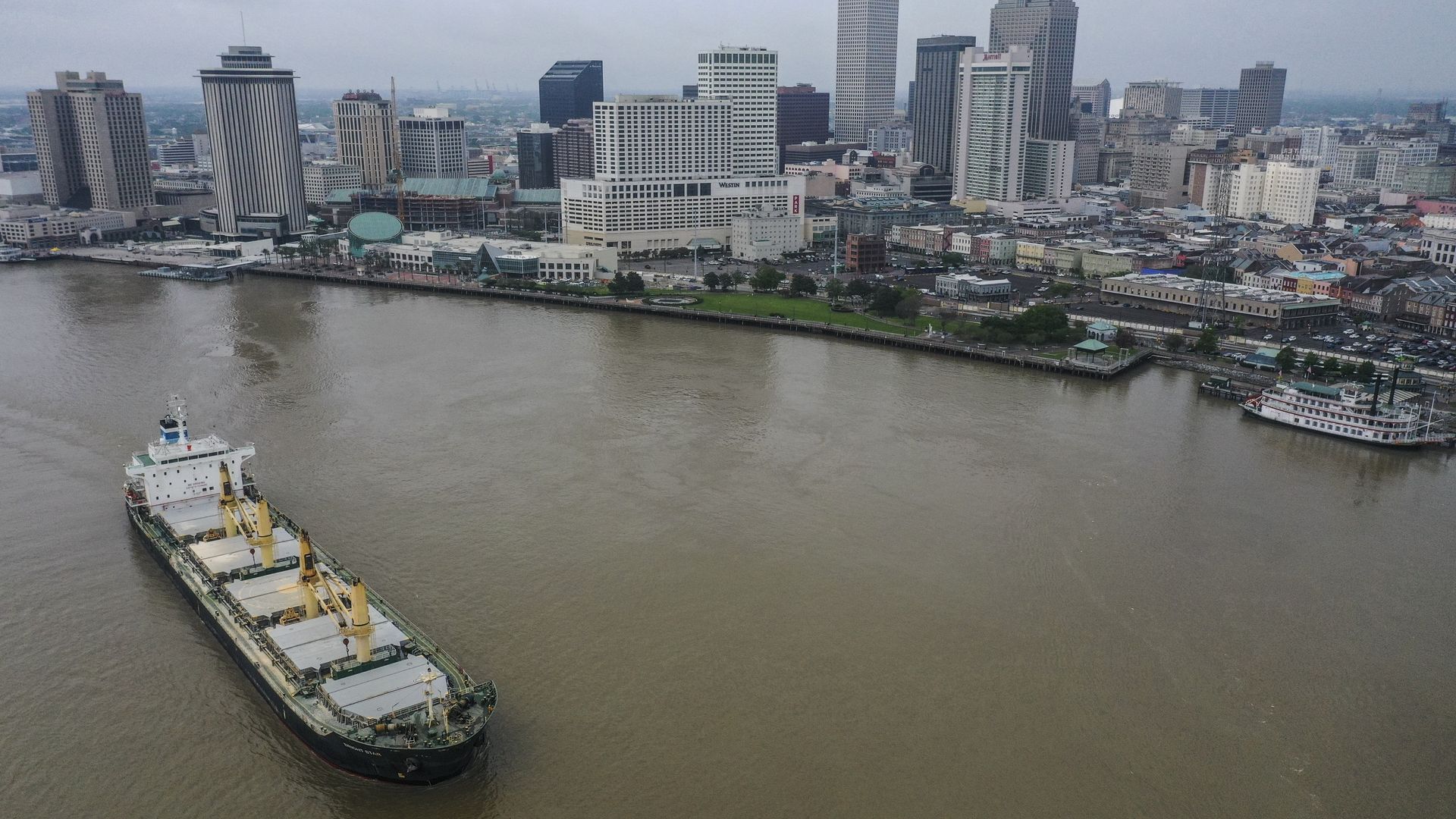 A barge on the Mississippi River and the downtown New Orleans skyline is seen from above.