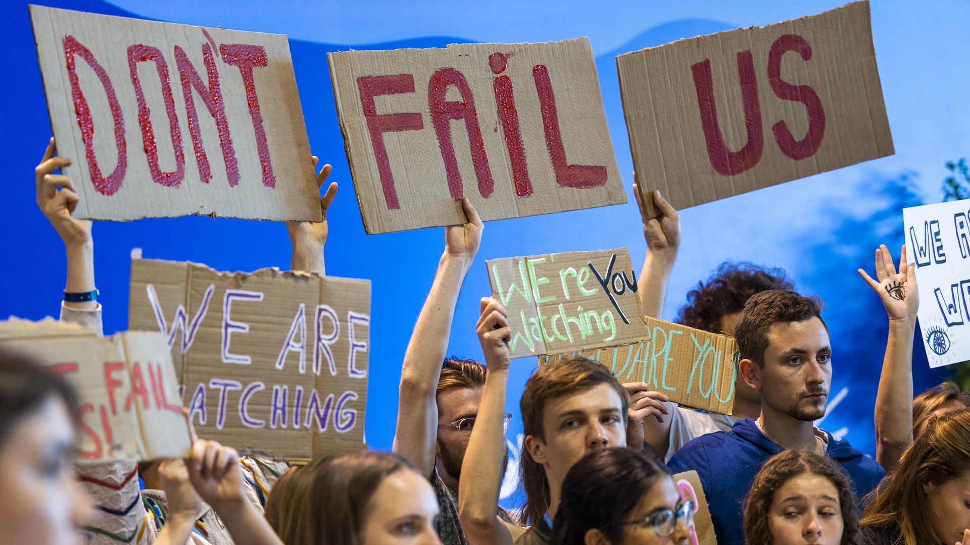 Young people hold up signs urging countries to take bold action against climate change at COP27 in Egypt.