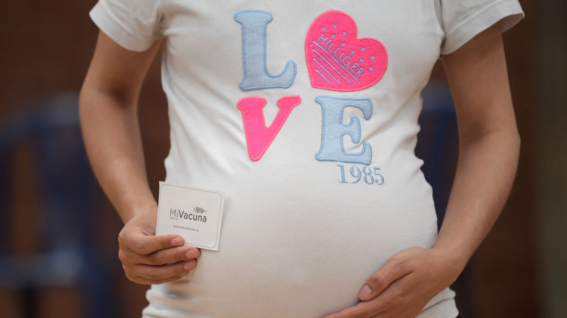 Pregnant woman showing her COVID-19 vaccination card