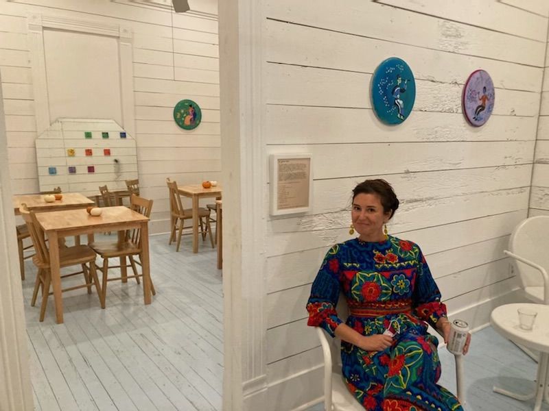 A photo of the artist in front of her artwork.