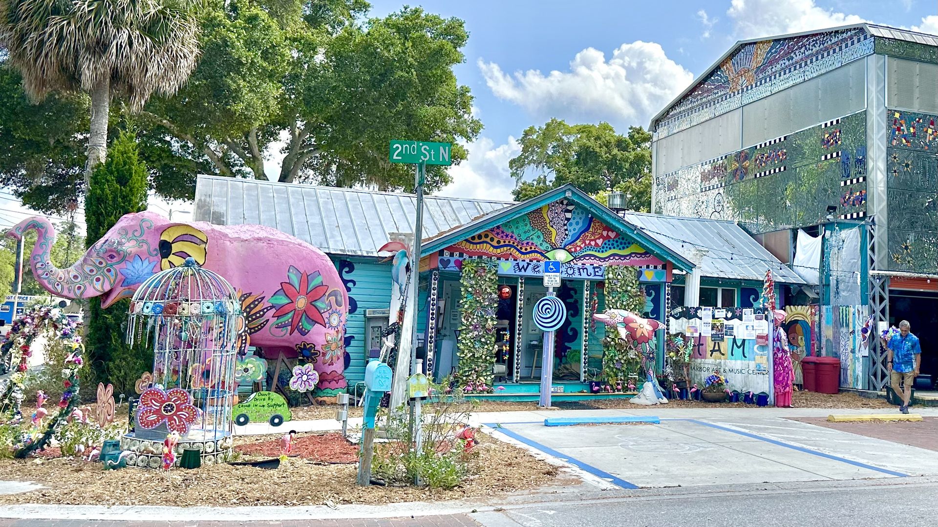 A home painted with swirly, colorful designs with a painted pink elephant in the front yard.