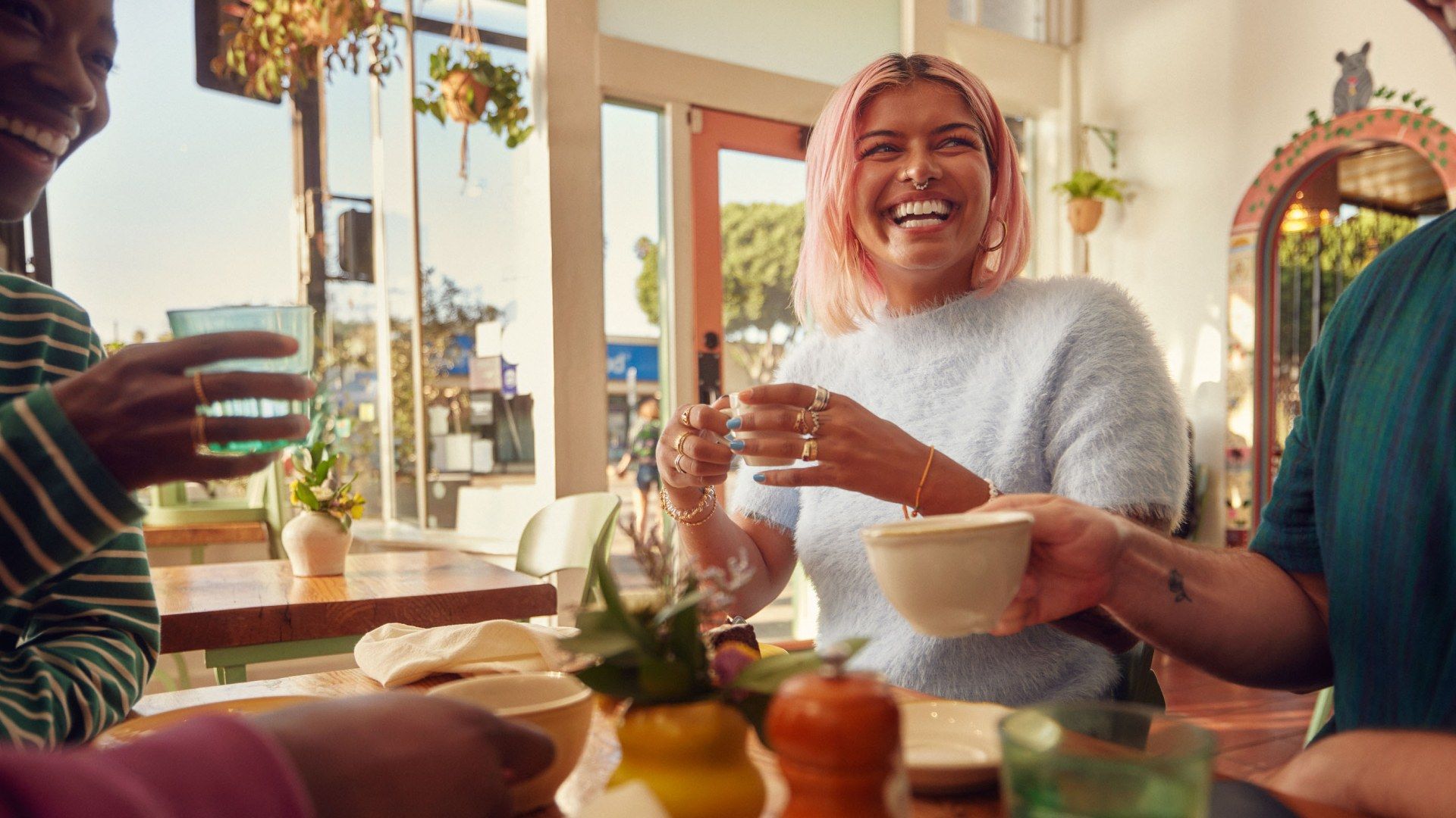  A group of people talking and laughing at a cafe.