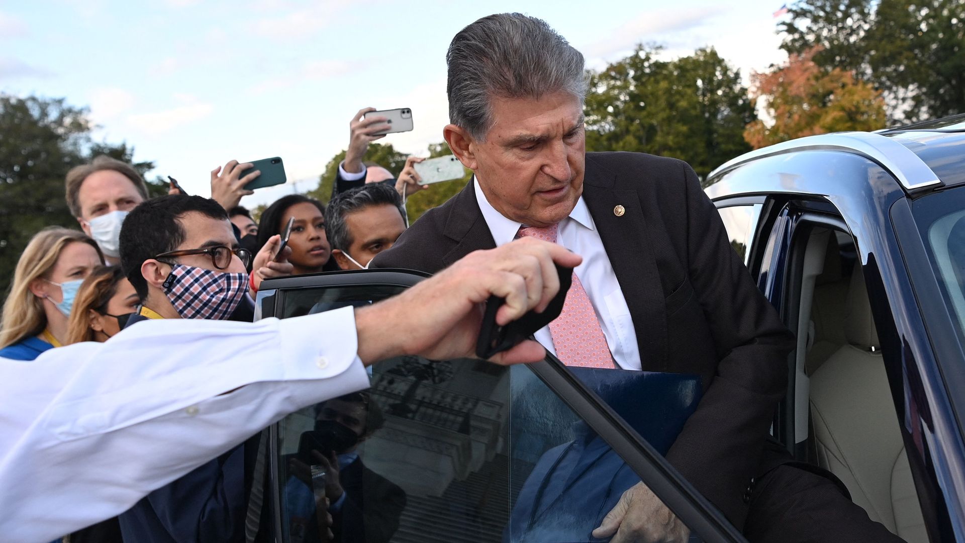 Sen. Joe Manchin is seen surrounded by reporters as he gets in a car on Thursday.