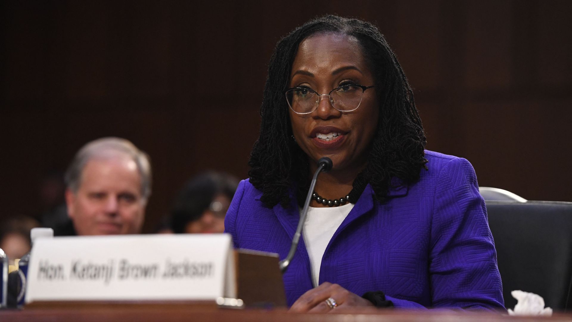 Photo of Ketanji Brown Jackson in a purple suit speaking into a mic