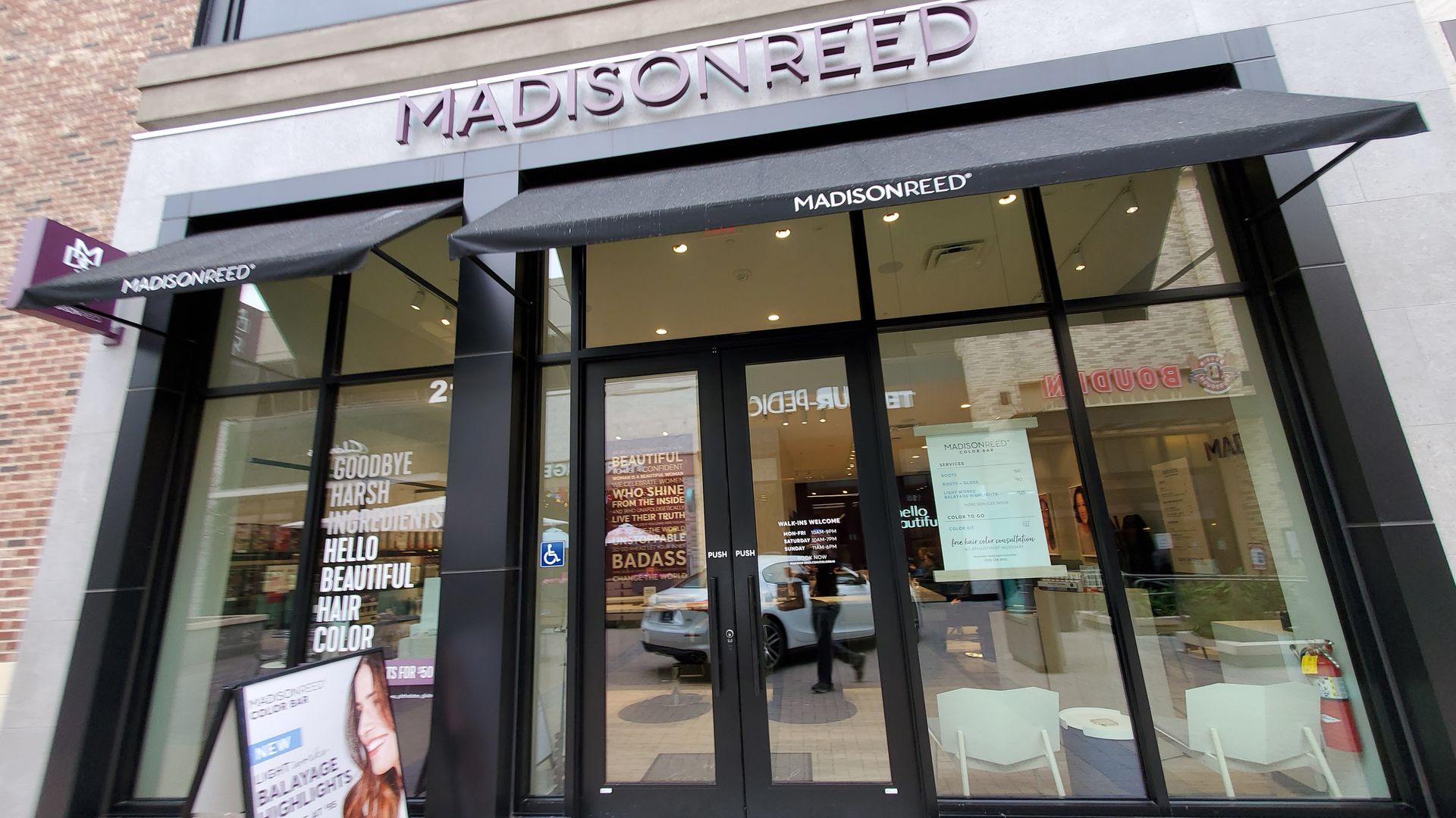 A Madison Reed banner hangs about a windowed storefront.