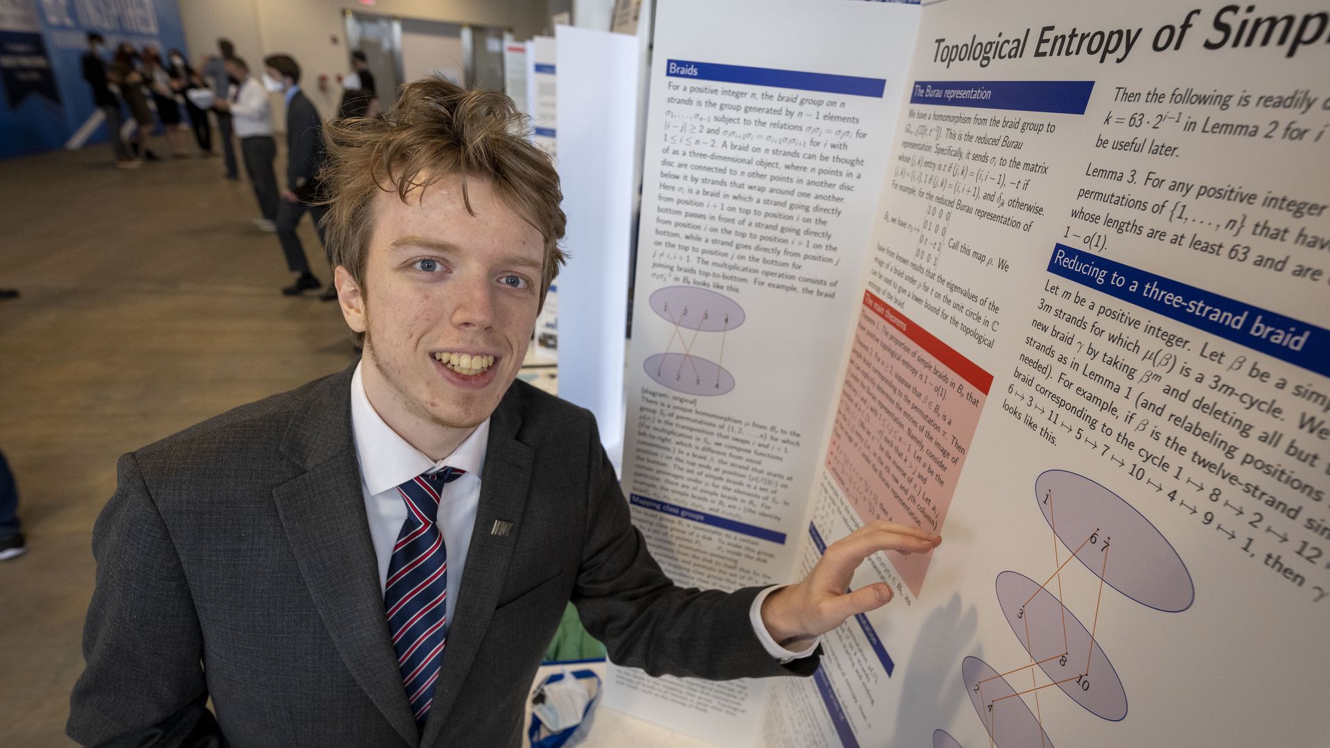 A young man stands next to a tri-fold science project