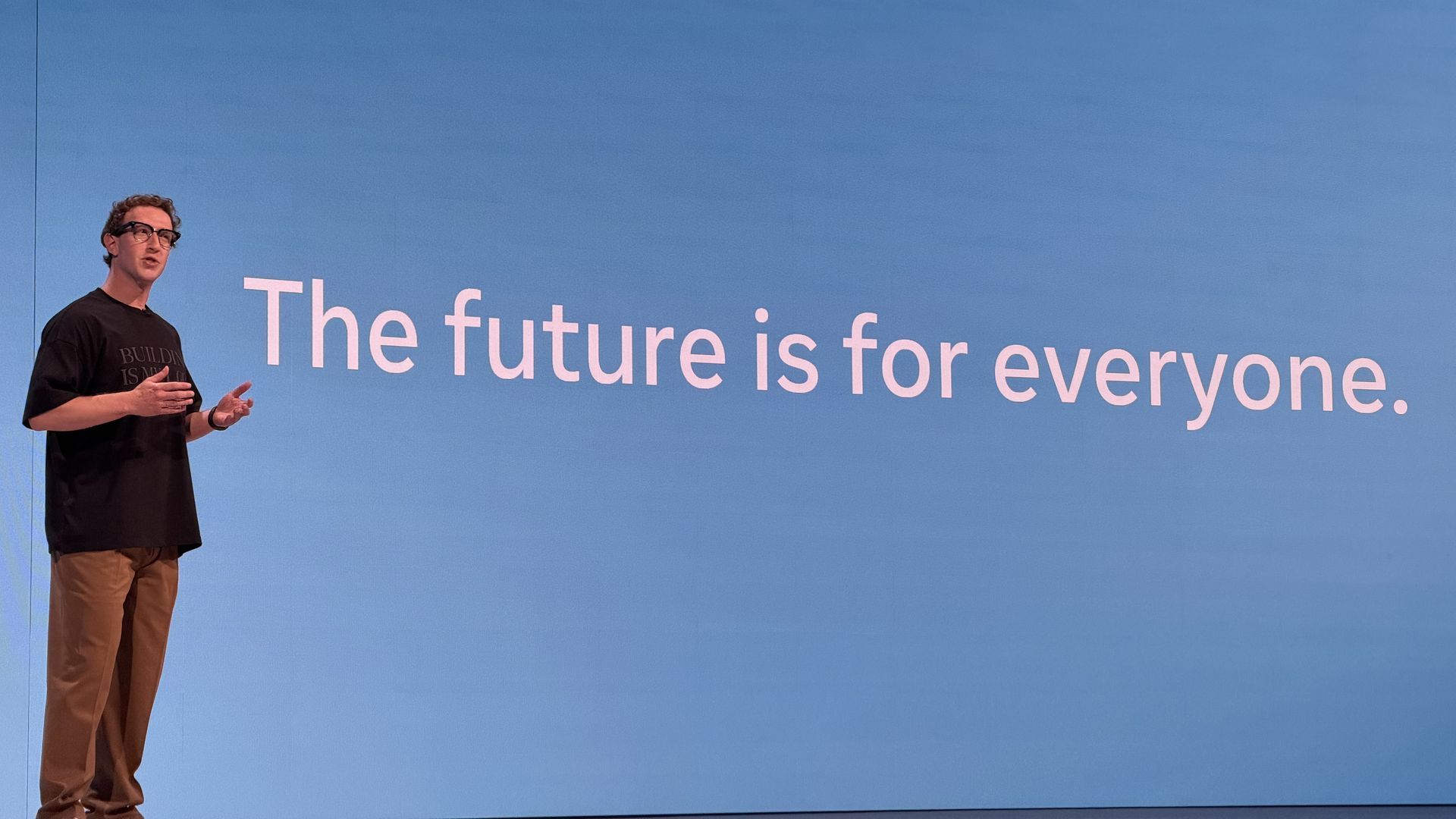 Mark Zuckerberg with glasses wearing a dark T-shirt stands on a blue stage with a large white slide reading The future is for everyone. A pink light stripe runs along the top.