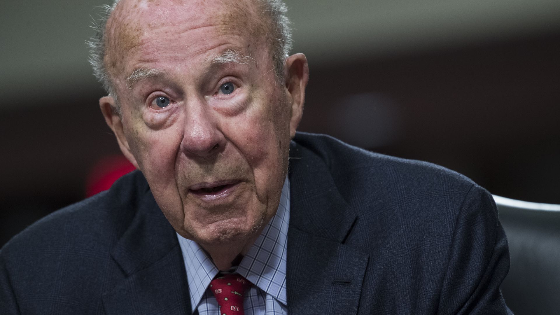 George Shultz in a red tie and a suit