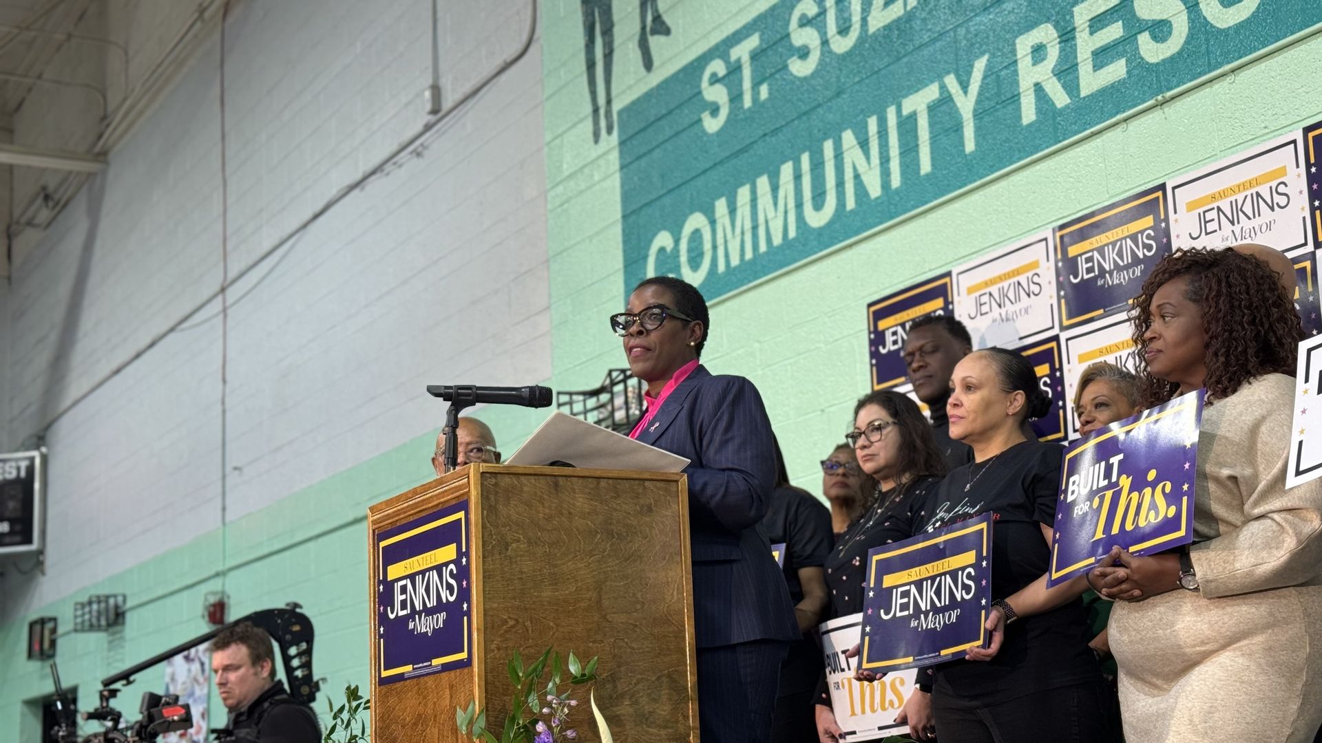Jenkins stands at a podium speaking with supporters behind her.