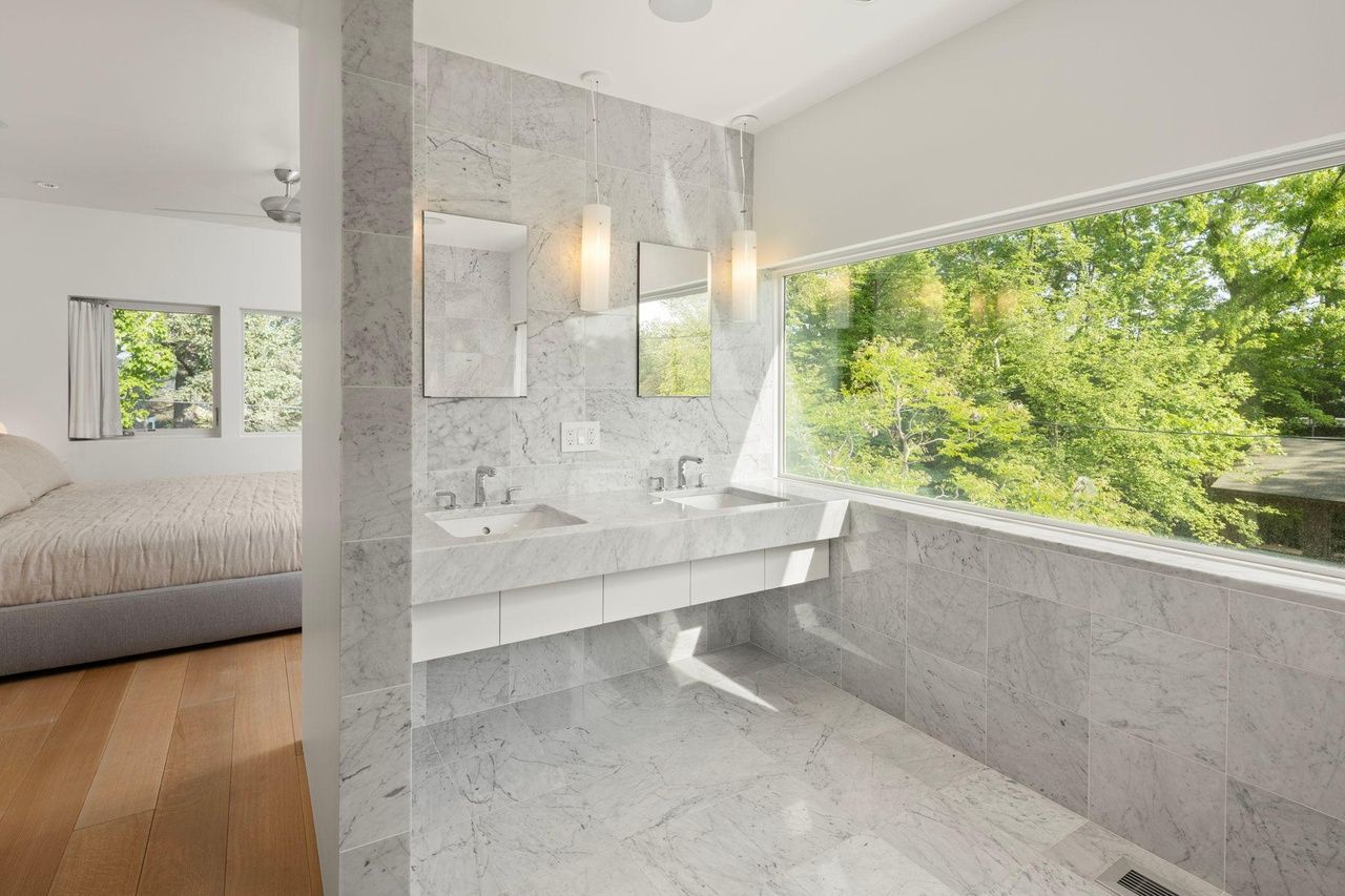 A photo of a bathroom with gray marble and large windows.