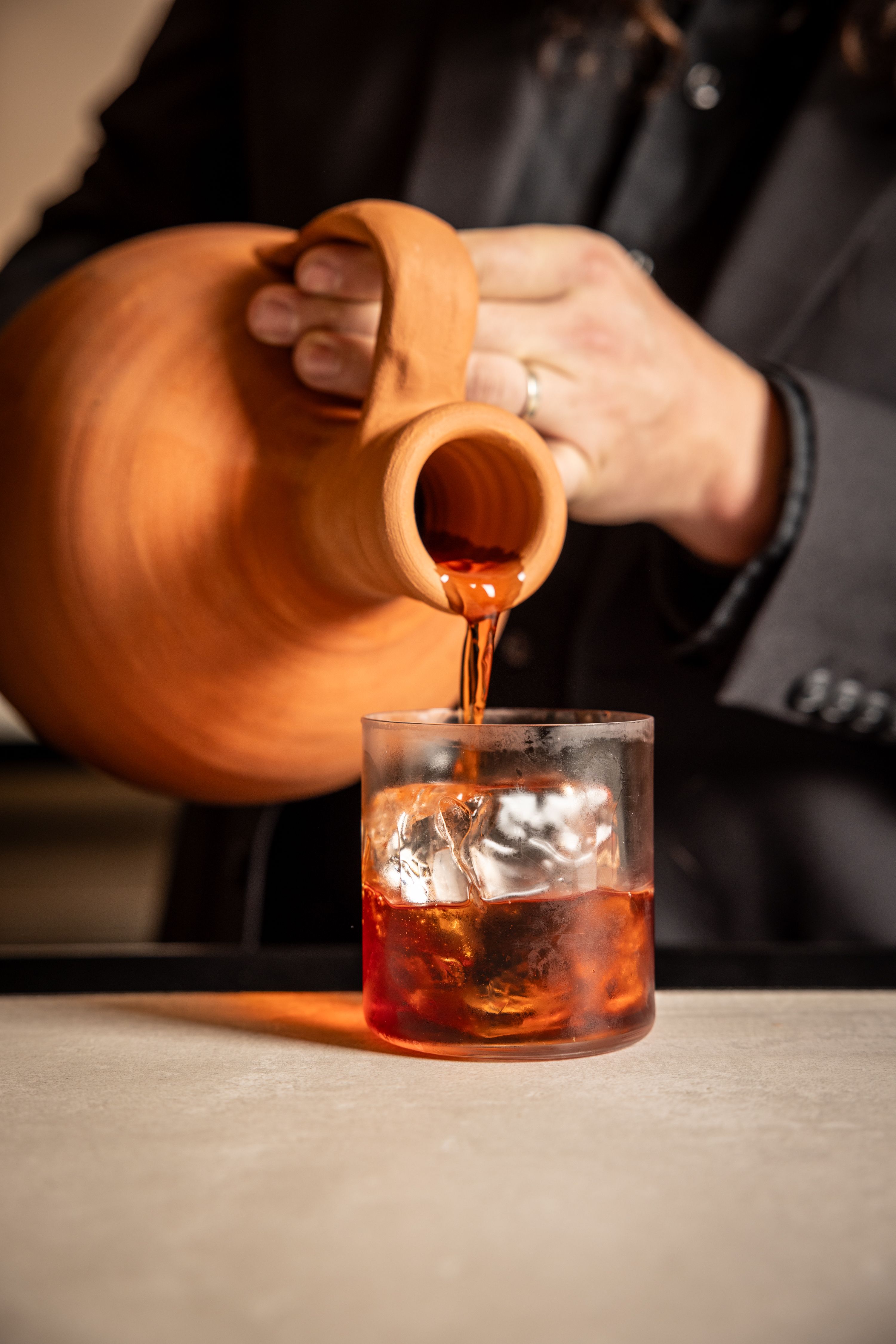 pouring a negroni from a clay pot