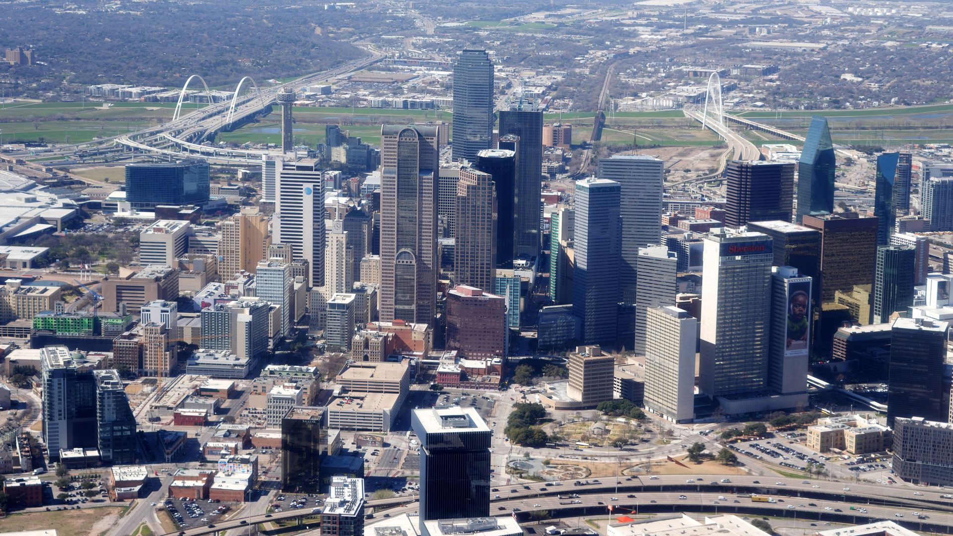 The downtown Dallas skyline with tall buildings and a white bridge to the left