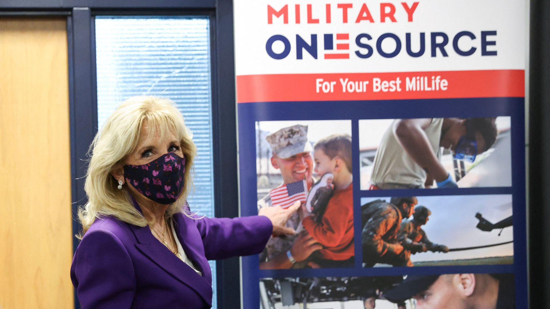 US first lady Jill Biden points to a military service member pictured on a sign as she tours Military One Source.