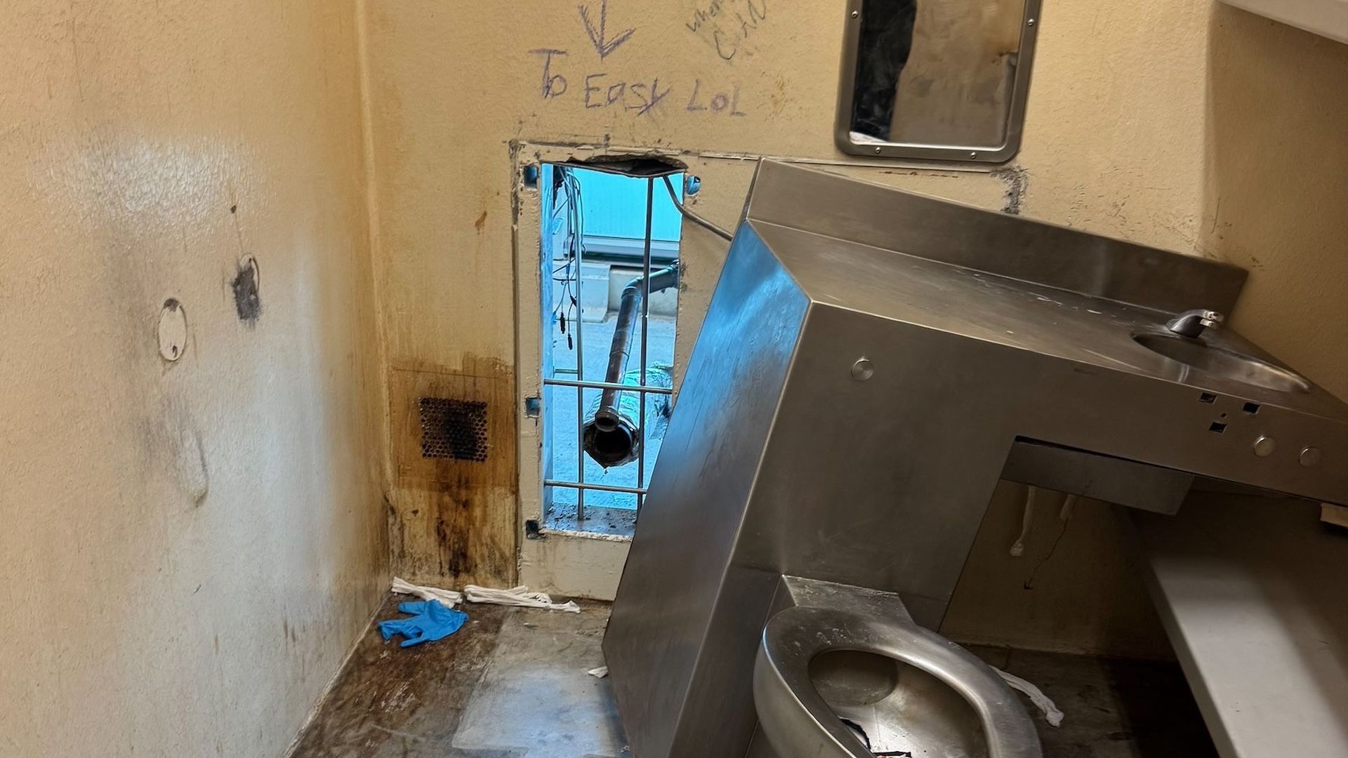 Photo shows a prison toilet with a hole behind it.