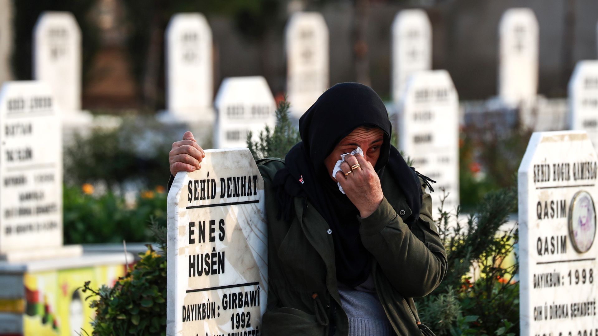 A Syrian Kurdish woman cries as she hugs the tombstone of a slain Syrian Democratic Forces fighter at a cemetery in the northeastern city of Qamishli 