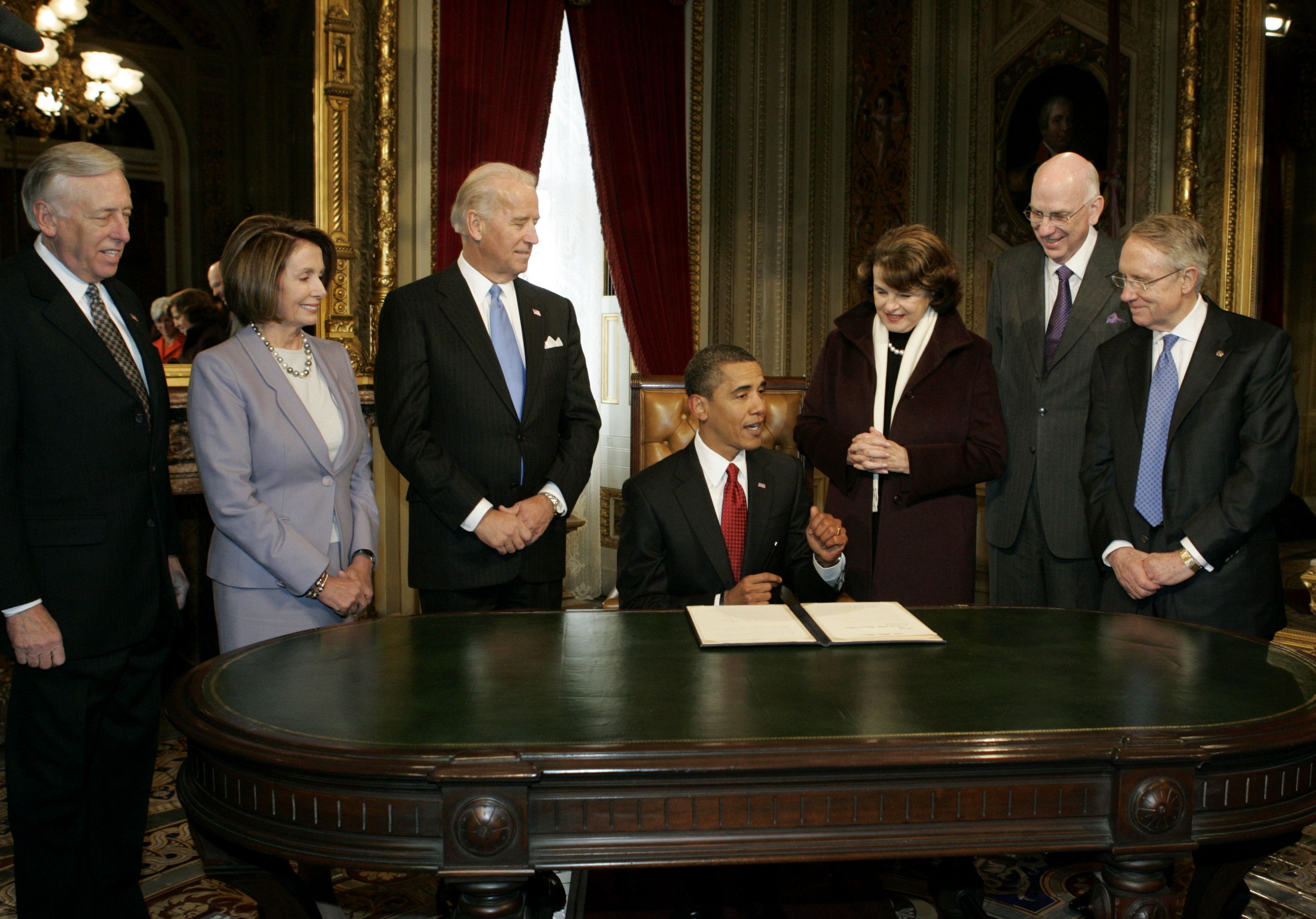 President Obama signs his first act as president at the Capitol, surrounded by congressional leaders including Nancy Pelosi, Joe Biden and Dianne Feinstein.