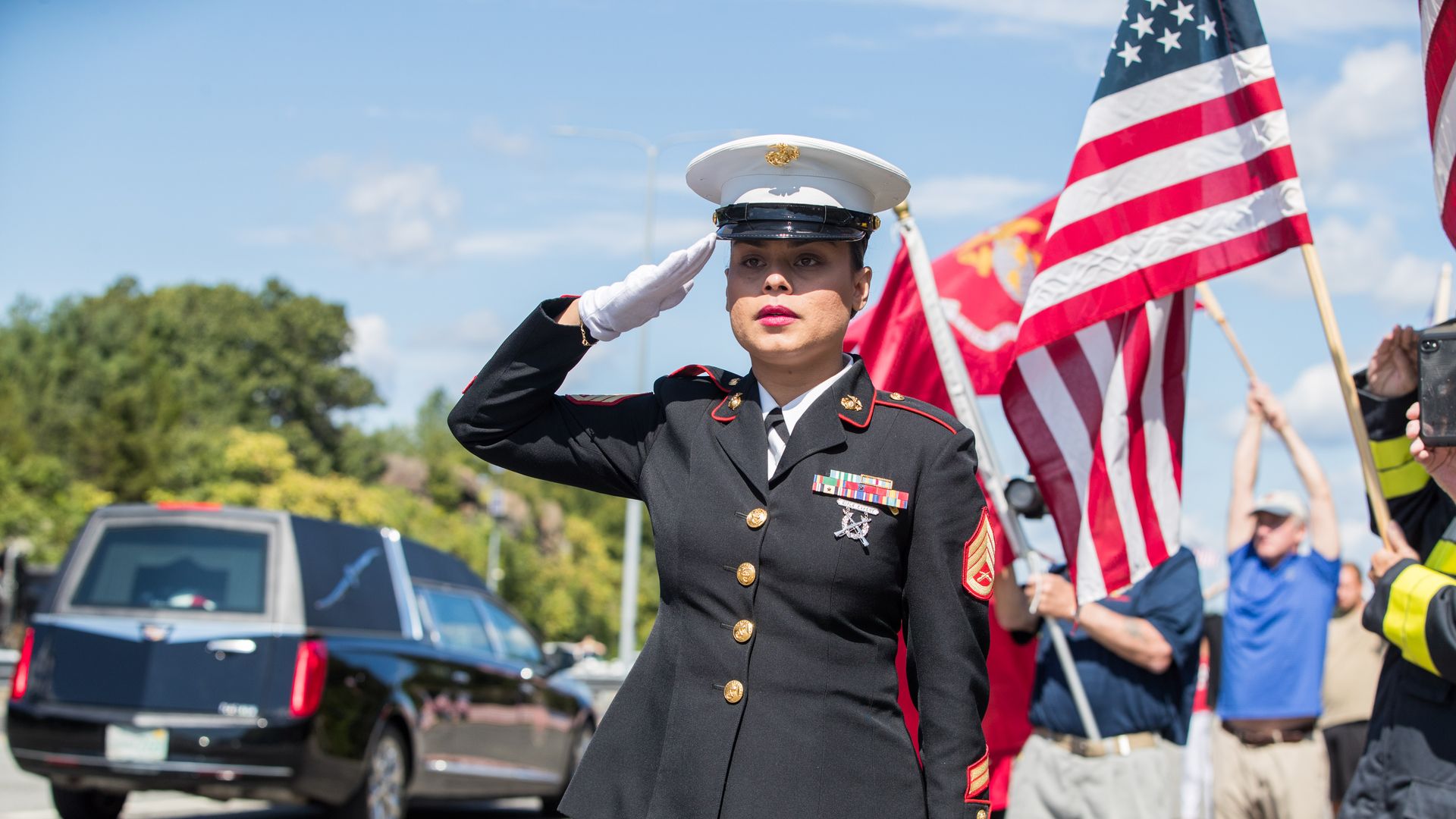 U.S. Marine Ssgt. Alice Ward stands at attention on the side of I-93 North as the hearse carrying fallen Marine Sgt. Johanny Rosario Pichardo passes on September 11