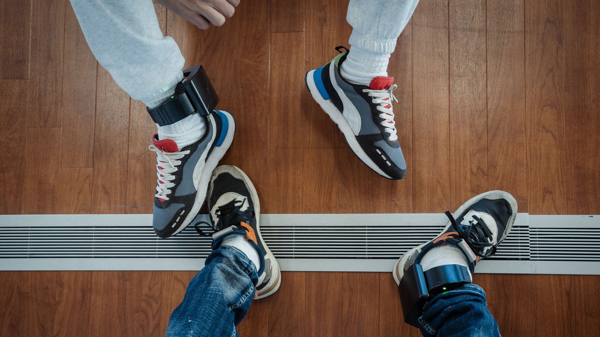 Ankle monitors on two people's feet.