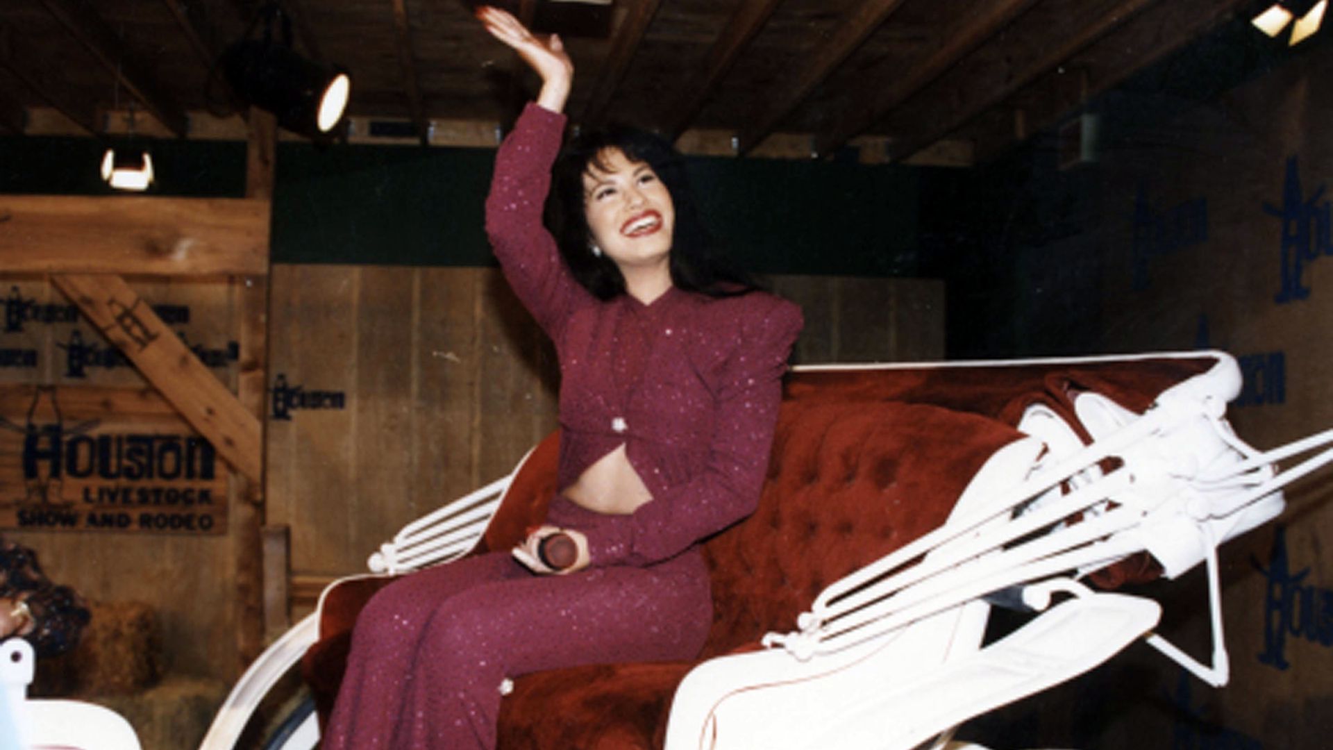 Selena sits in a horsedrawn carriage while she waves to fans. 