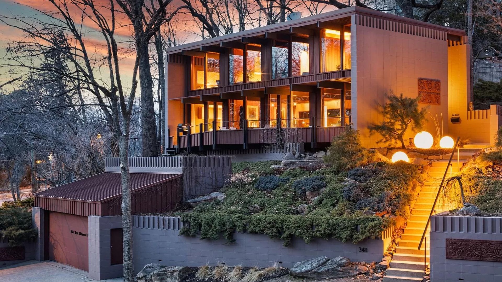 A photo of a house with walls of windows as seen at sunset.