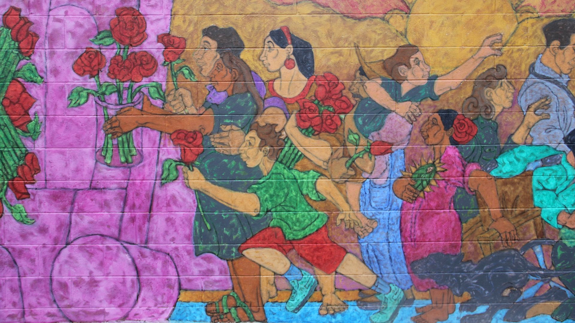 Colorful mural depicting people carrying and reaching for red roses, with a large yellow sun in the background.