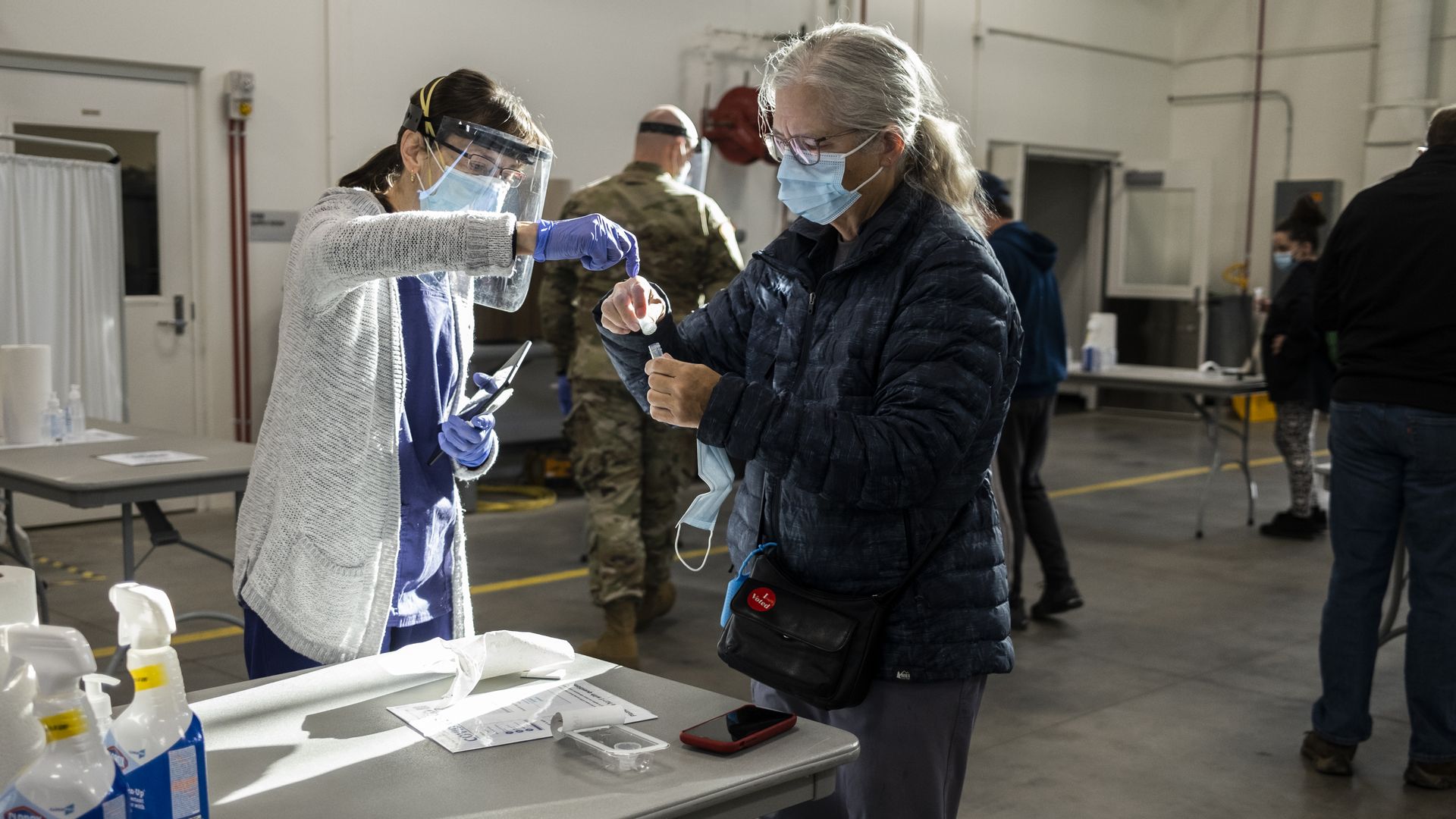 Photo of a masked person getting tested as a health care worker assists them
