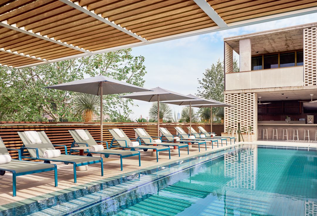 A photo of a pool with chairs along the side.