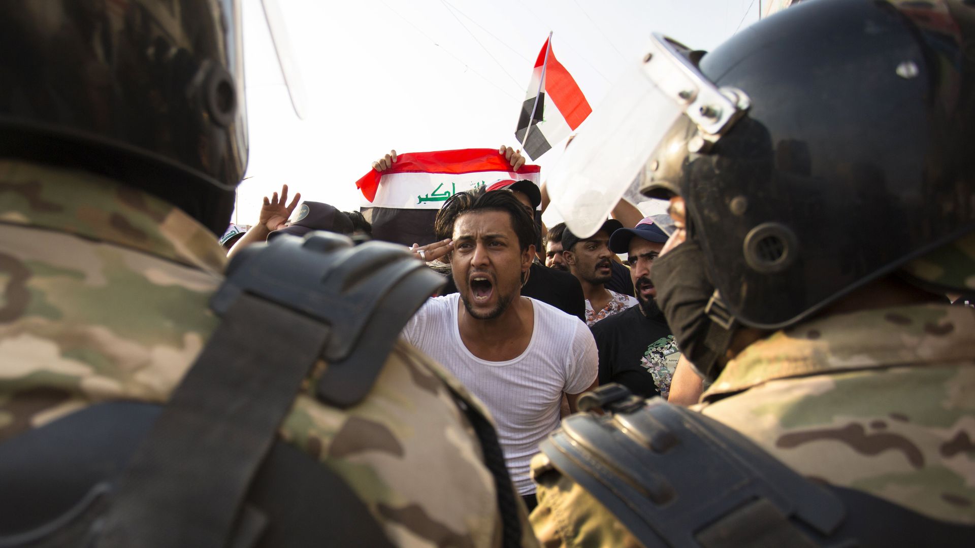 Iraqi protester gestures in front of armed forces 