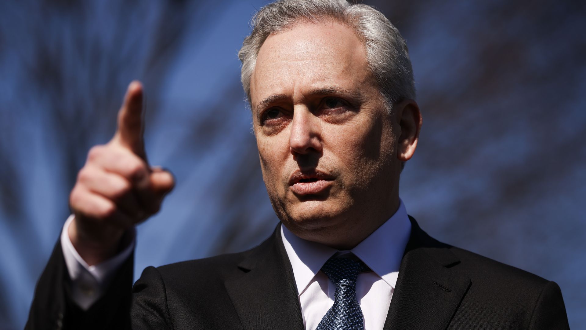 A person in a suit and tie points a finger