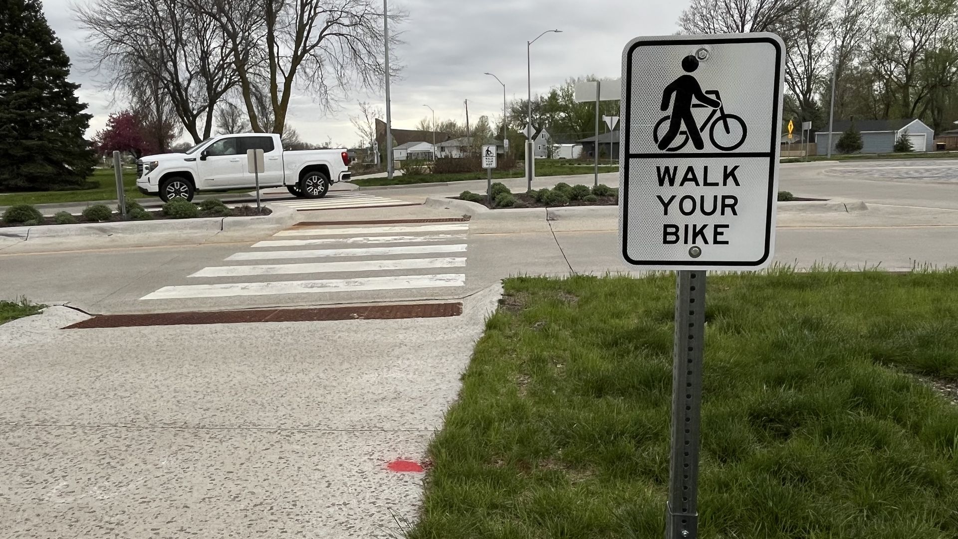 a crosswalk with "walk your bike" sign in front of it