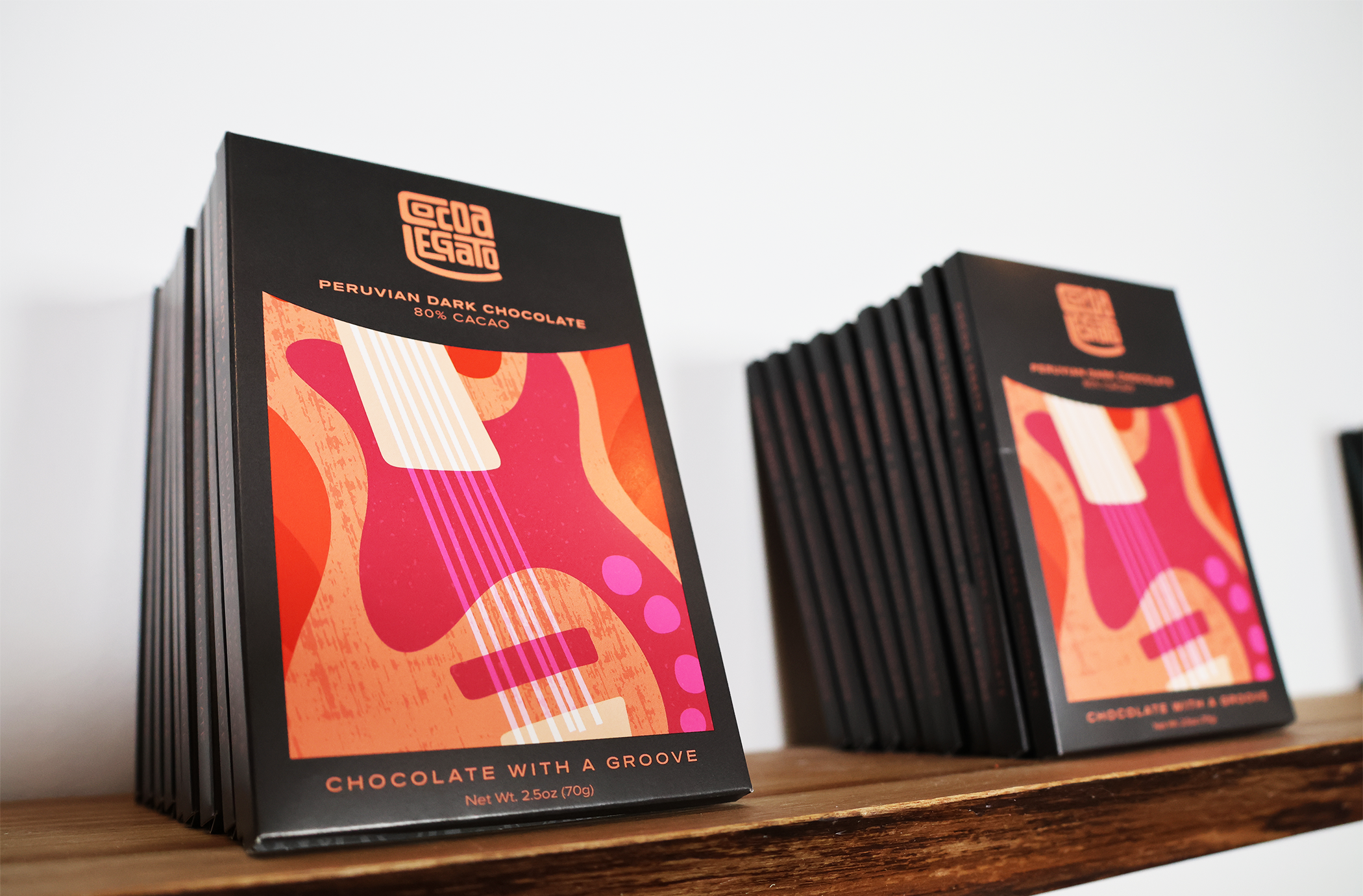 Bars of chocolate sourced from Peru sit on a shelf in a row, with a guitar-like image on the wrapper.