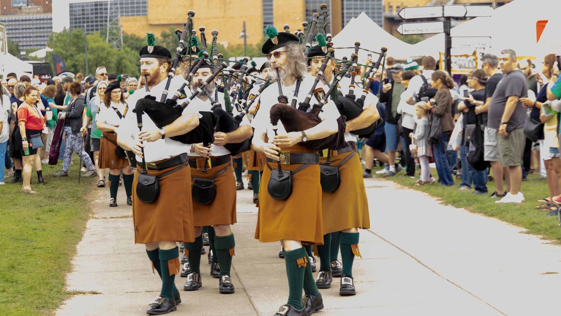 A Photo Shows A Group Of Bagpipers Playing And Walking Down A Path